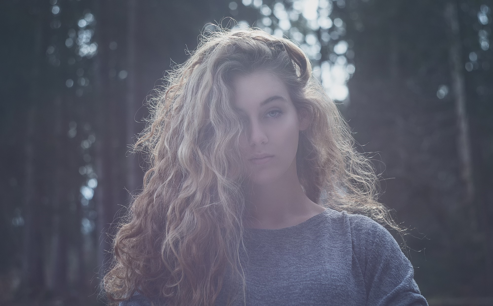 Woman with long curly blonde hair in a grey sweater outdoors HD Wallpaper