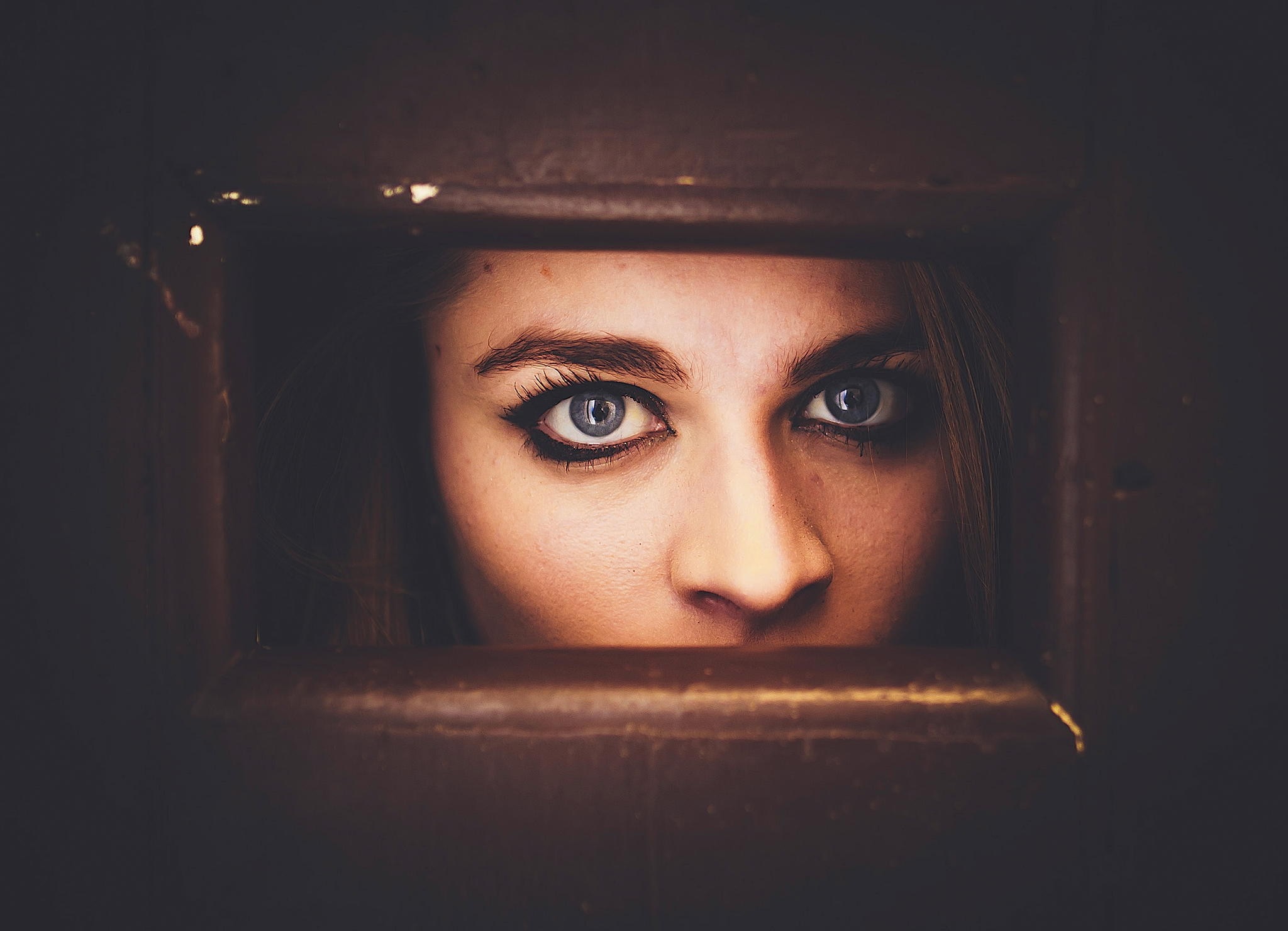 Close up of a woman's blue eyes looking through a wooden frame HD Wallpaper