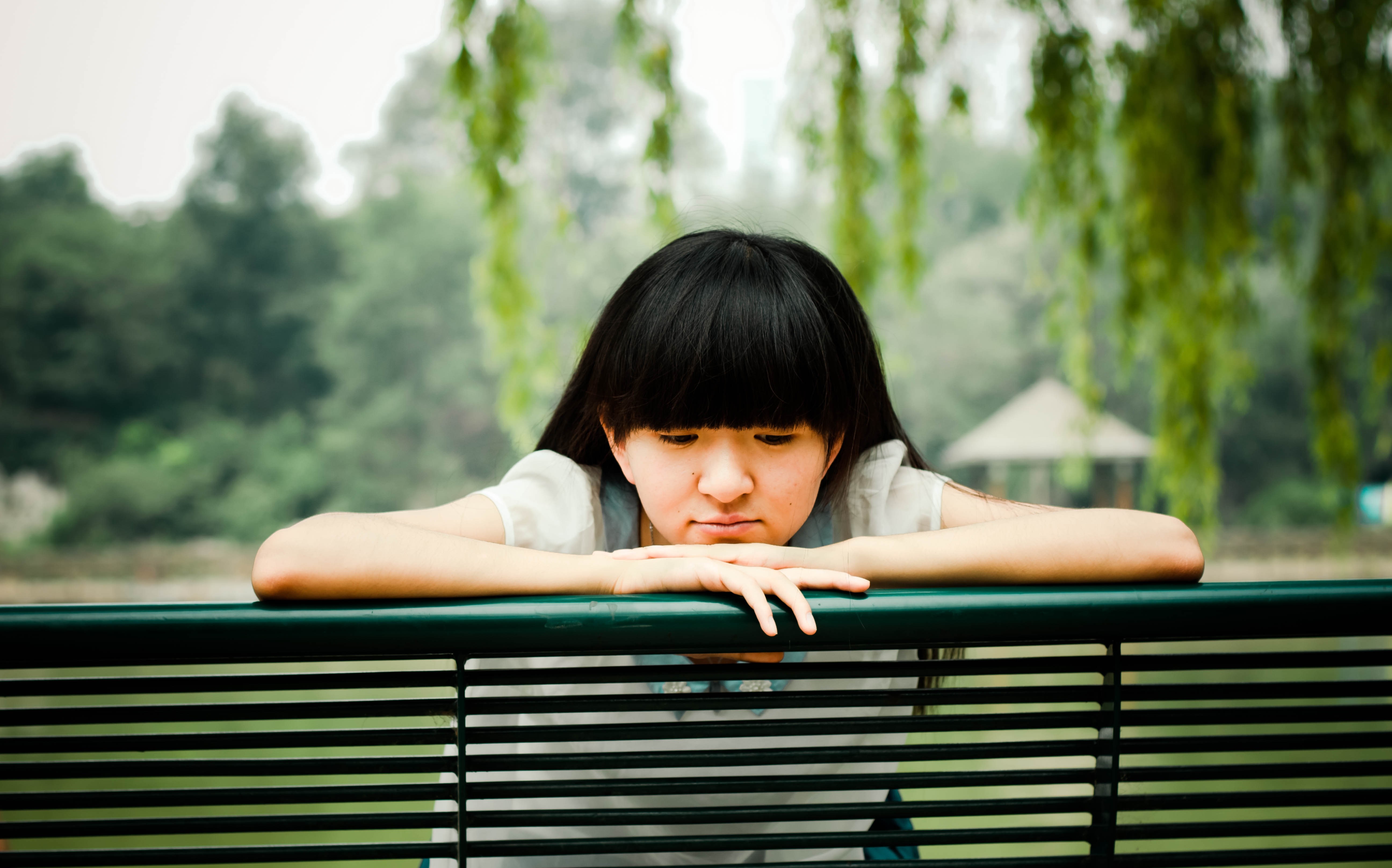 Young Asian woman sitting on a park bench HD Wallpaper