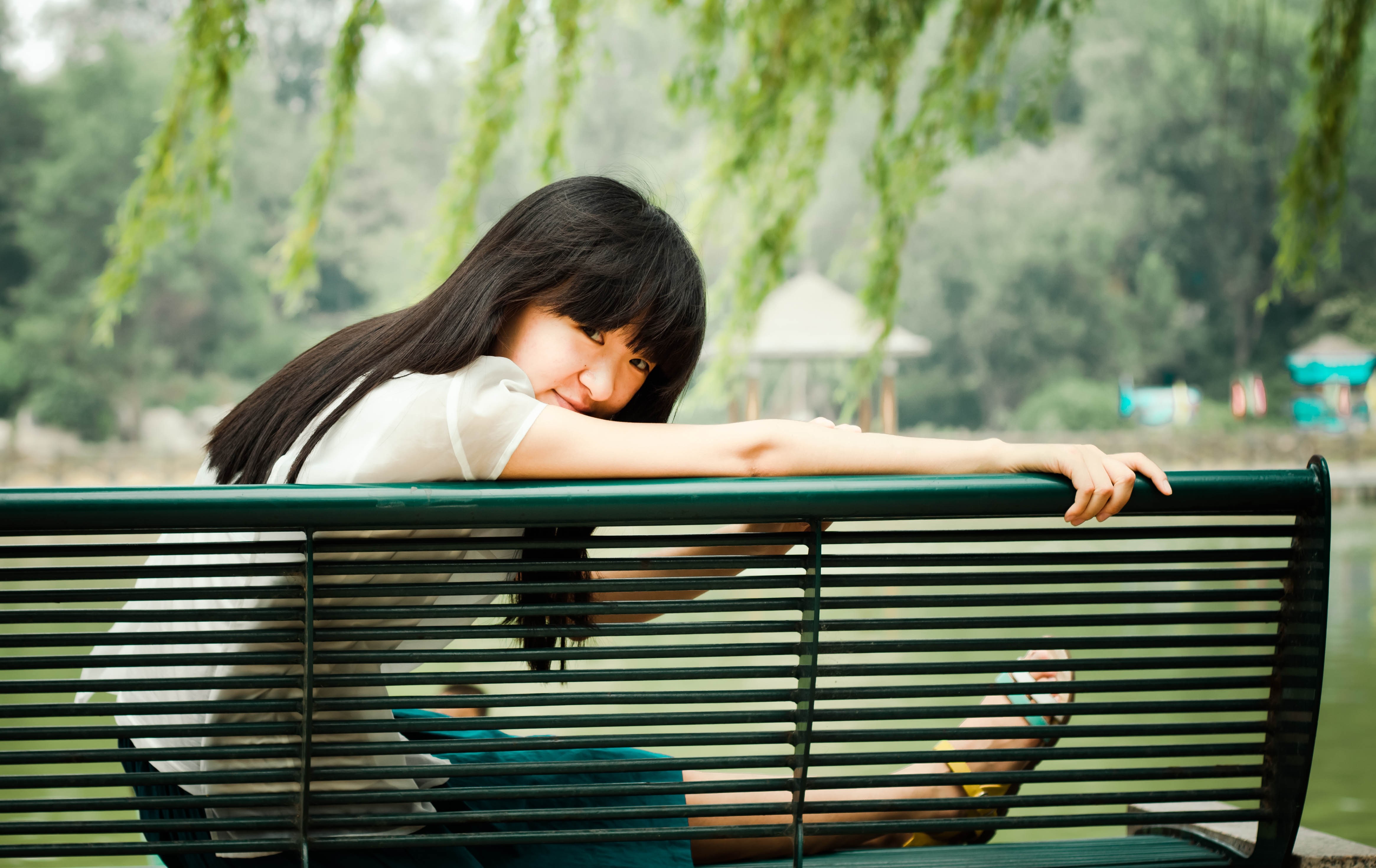 Young Asian woman sitting on a park bench HD Wallpaper