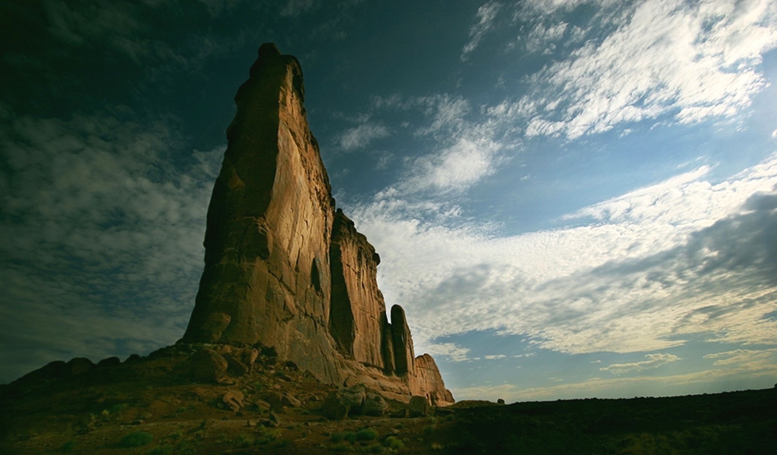 Tall rock formation under a cloudy sky HD Wallpaper