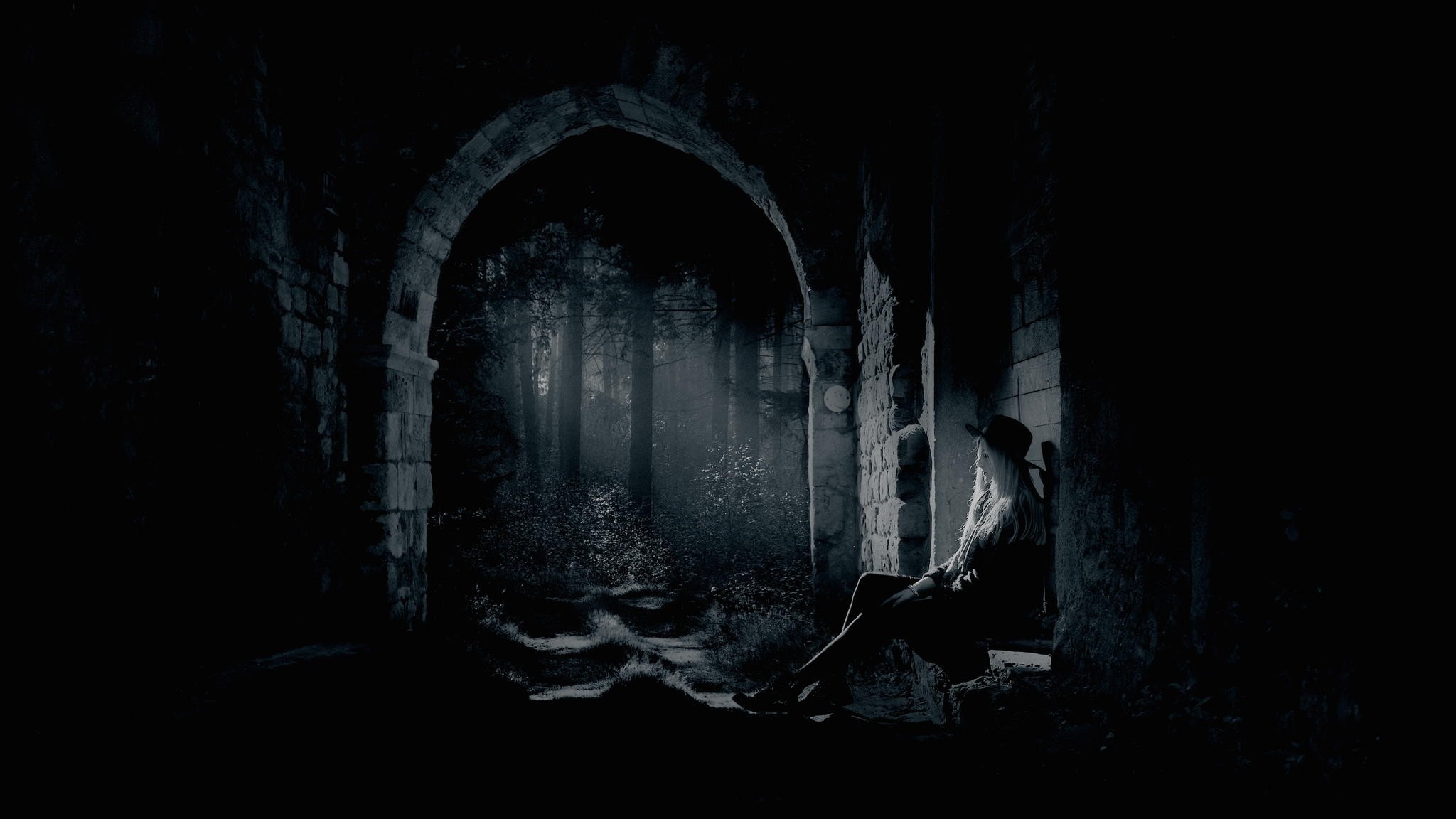 Woman sitting in dark stone archway looking at forest HD Wallpaper