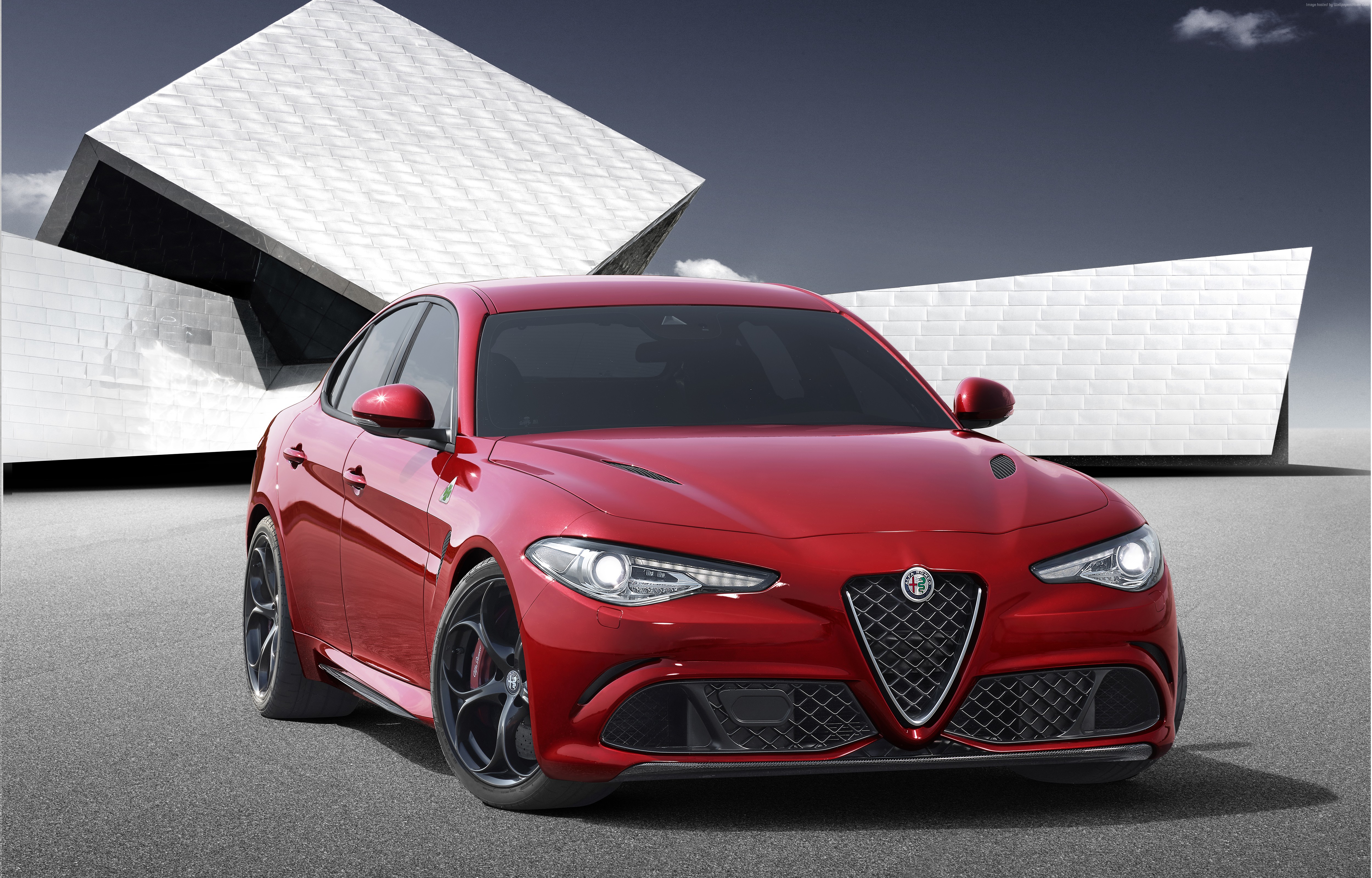 Red Alfa Romeo Giulia in front of modern architecture HD Wallpaper