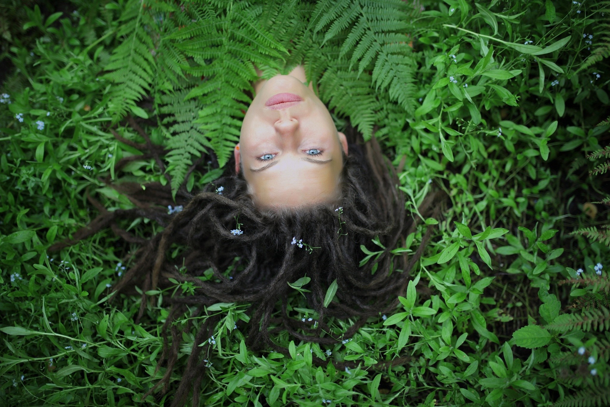 Woman with dreadlocks lying in green foliage HD Wallpaper