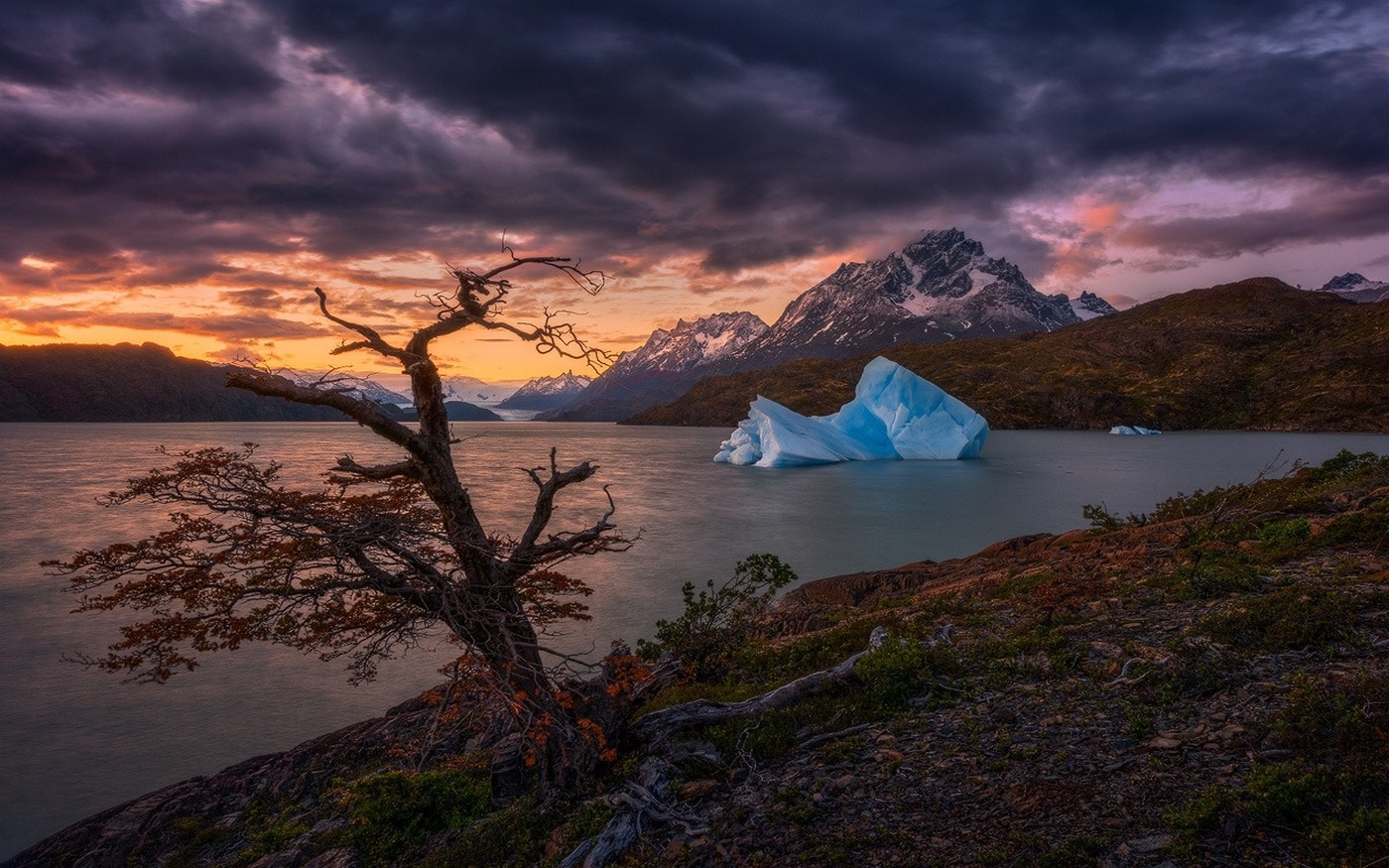 Iceberg in a lake at sunset with mountains and tree HD Wallpaper