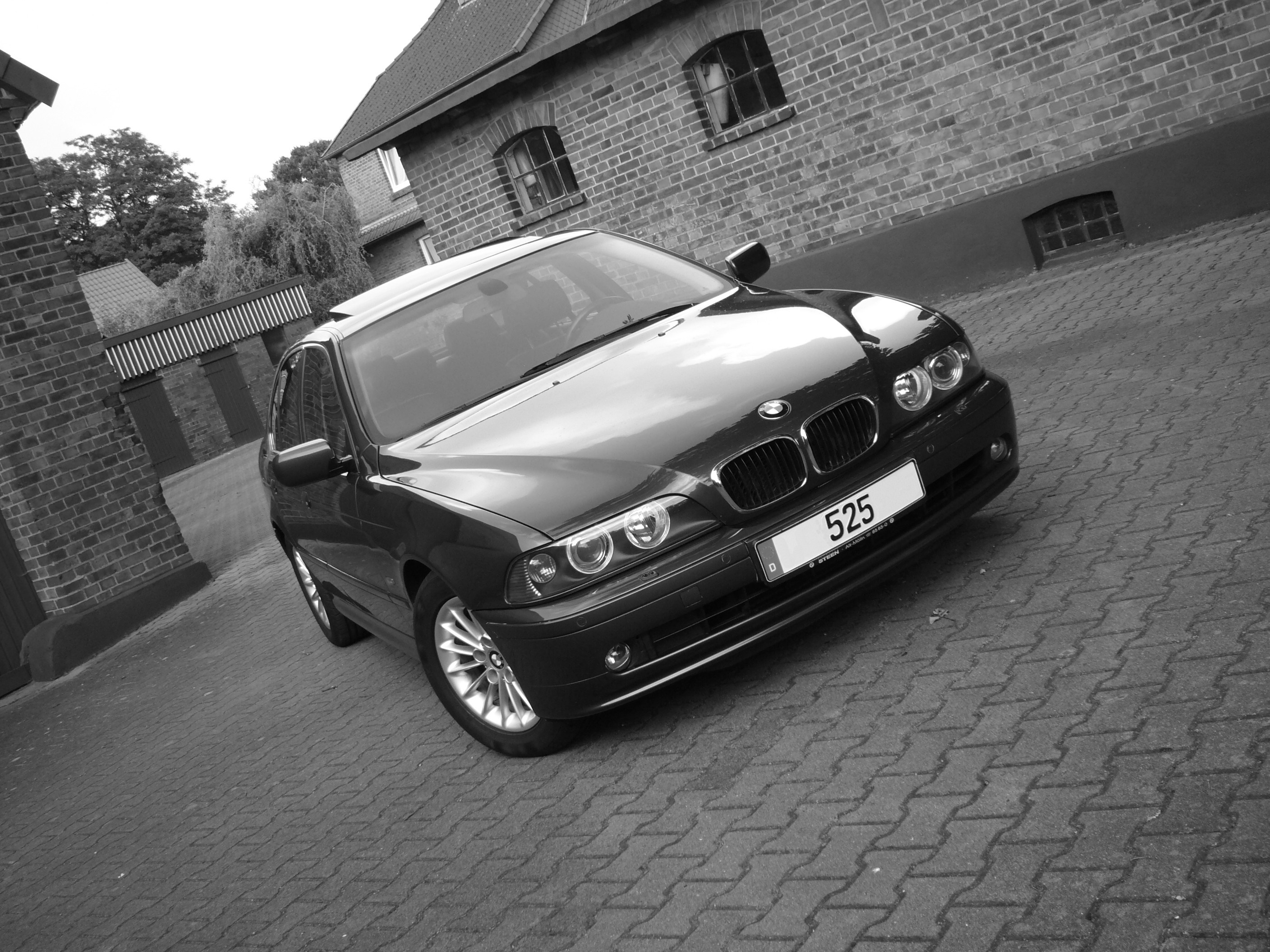 Black BMW 525 Sedan parked on cobblestone street HD Wallpaper