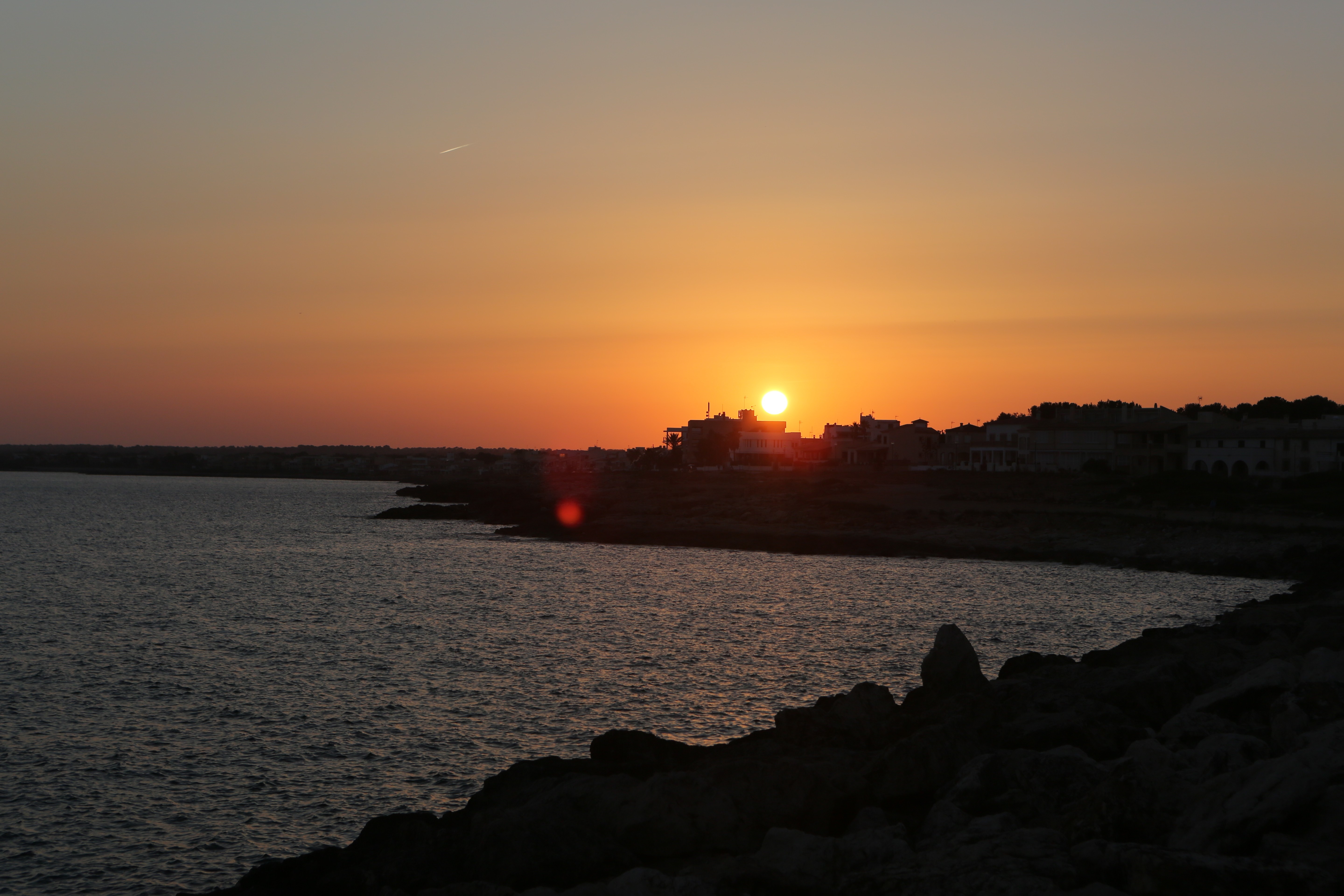 Sunset over the sea with a coastal town HD Wallpaper