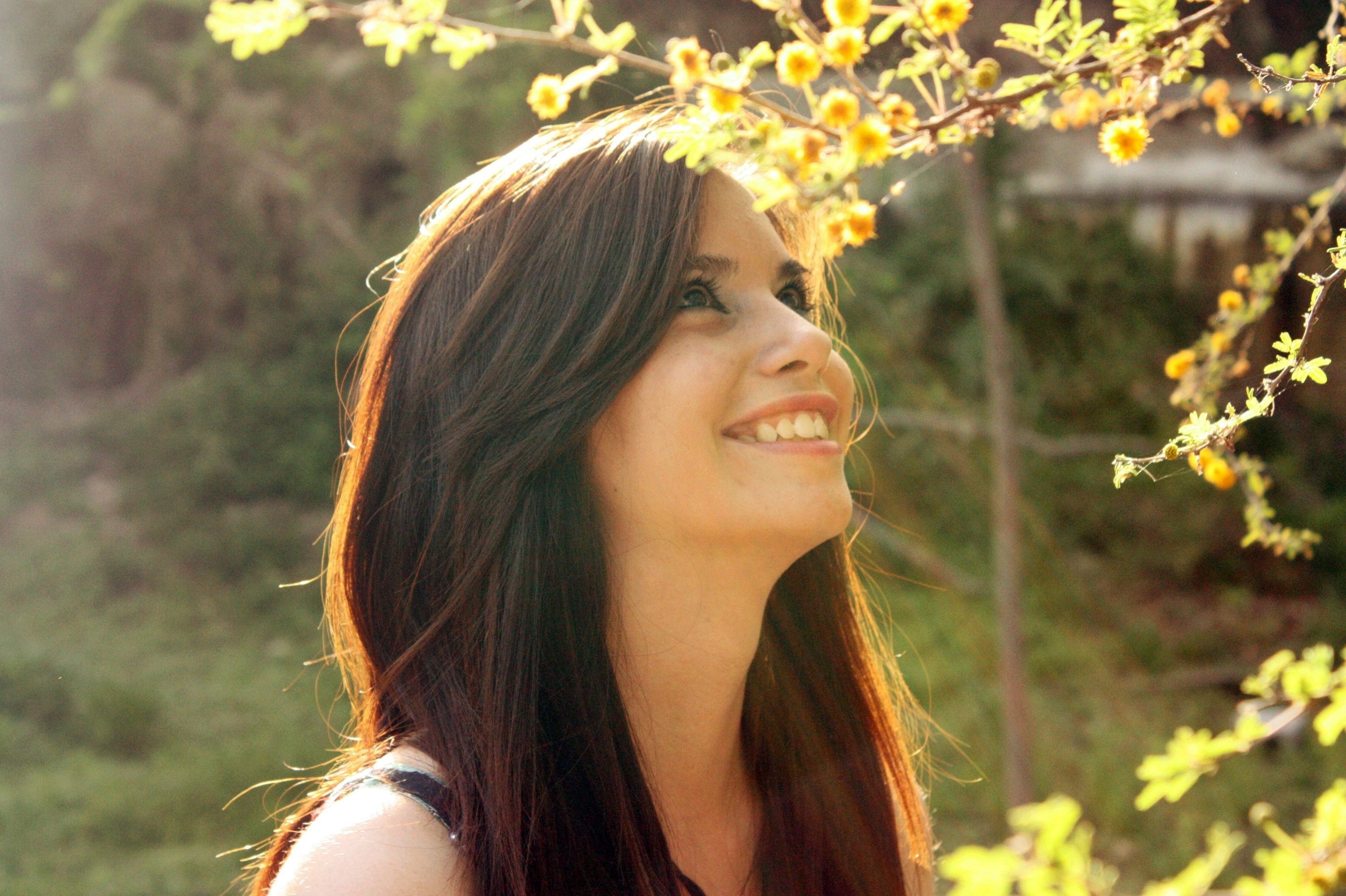 Woman smiling under yellow flowers HD Wallpaper