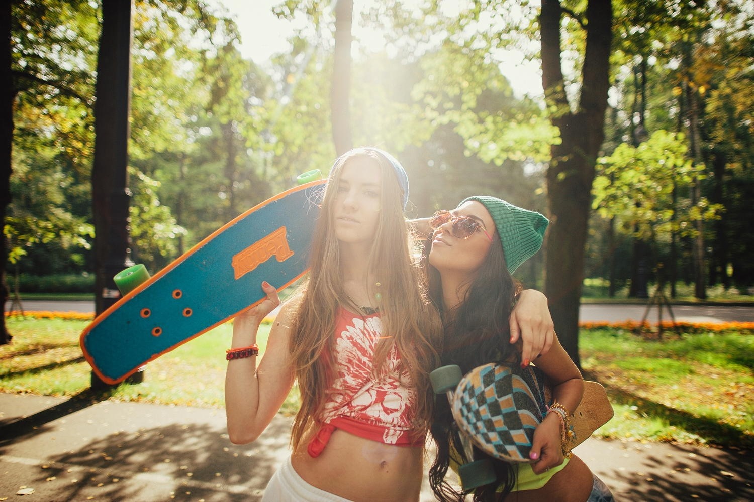 Two young women with skateboards in a park HD Wallpaper