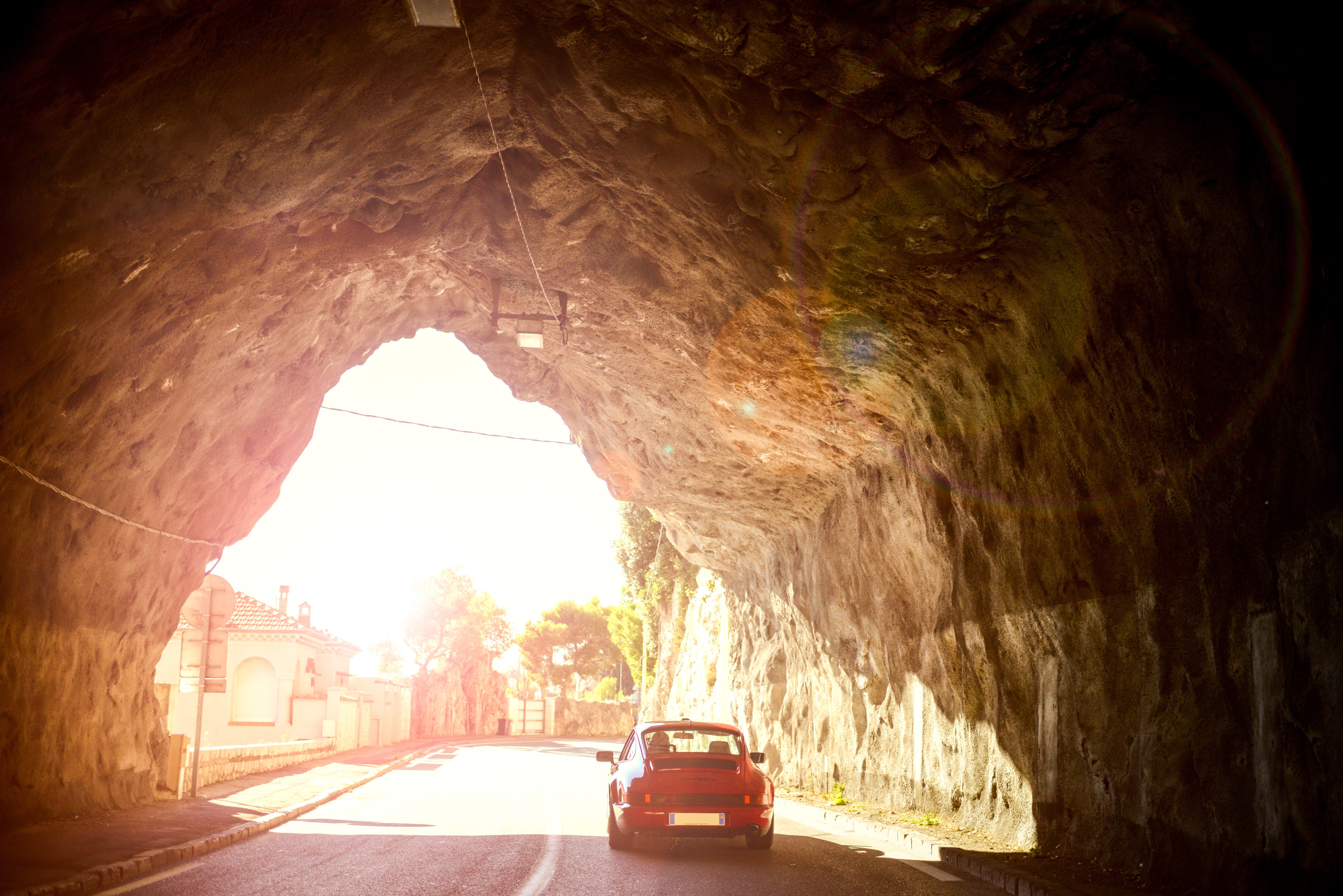 Red Porsche 911 driving out of a rock tunnel HD Wallpaper
