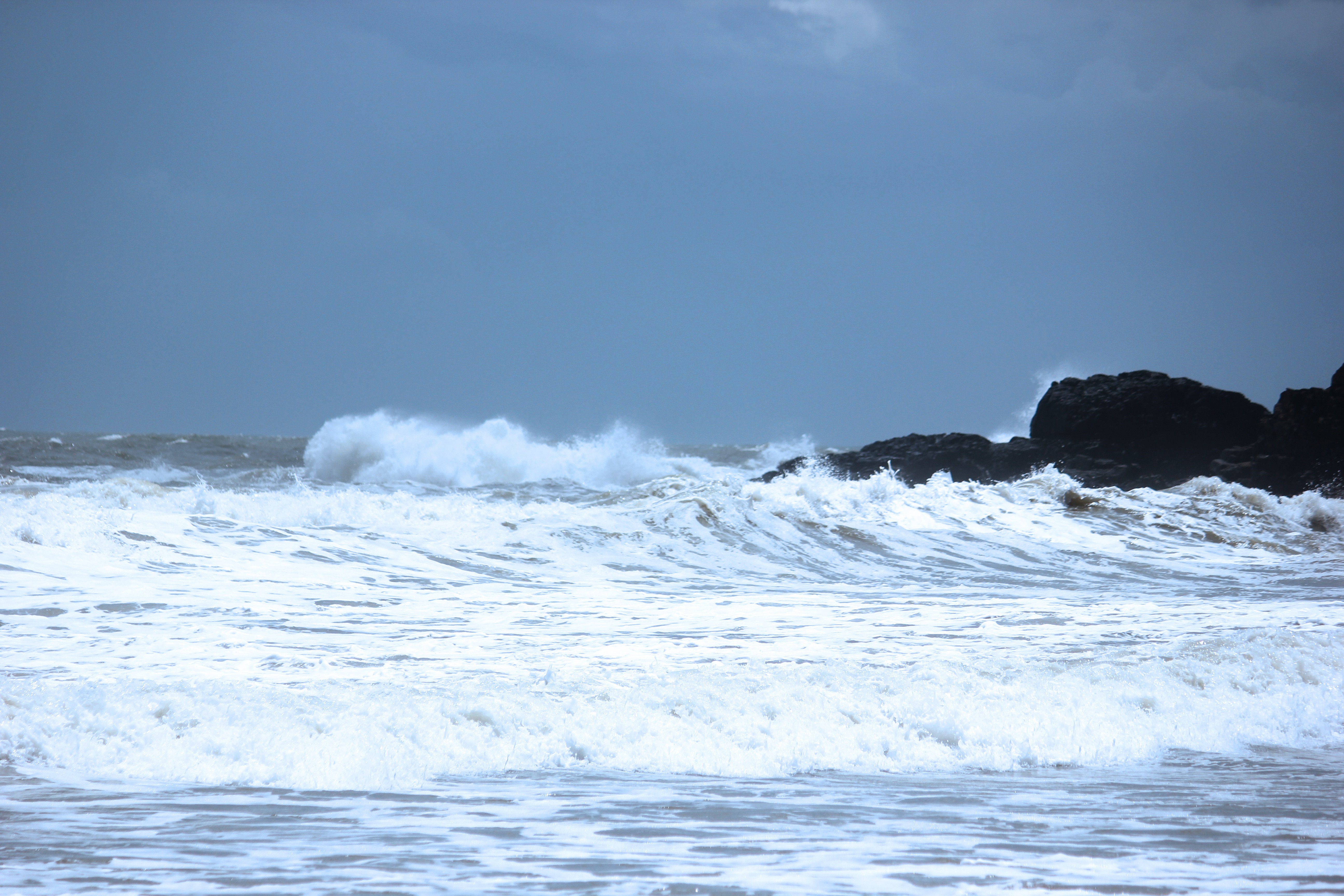 Waves crashing on rocks under a cloudy sky HD Wallpaper