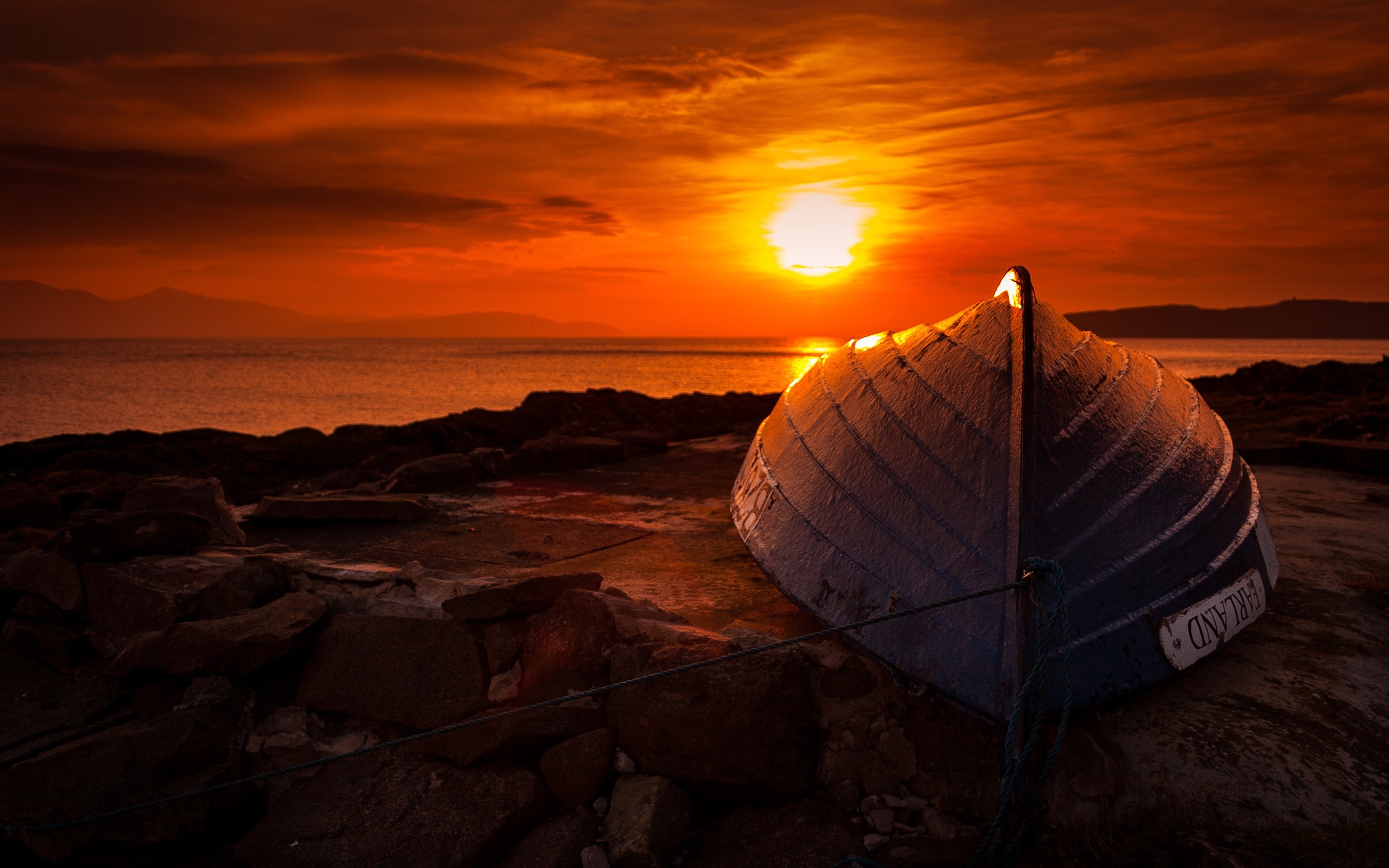 Boat on rocky shore at sunset HD Wallpaper