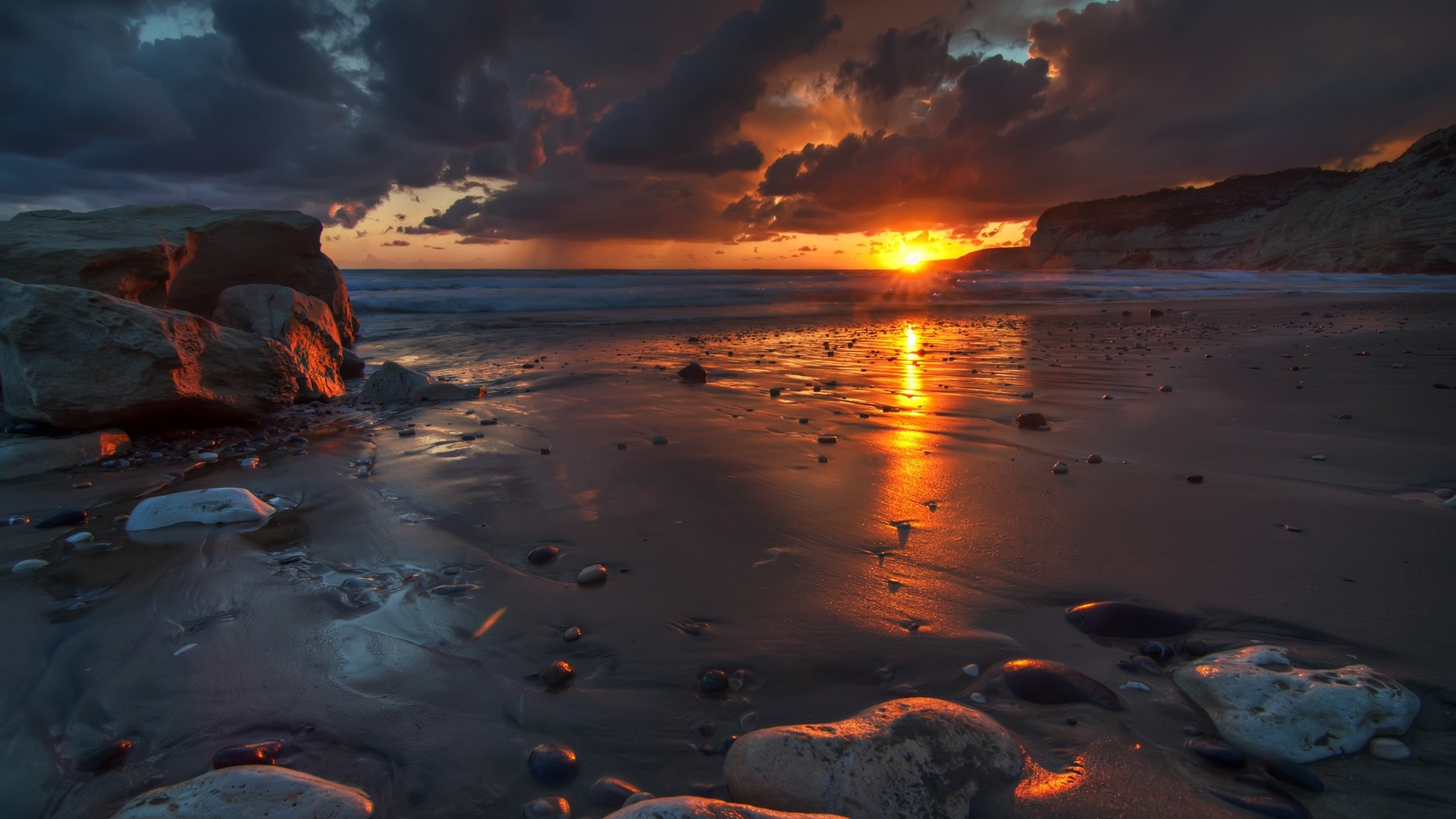 Sunset over a rocky beach with dramatic clouds HD Wallpaper