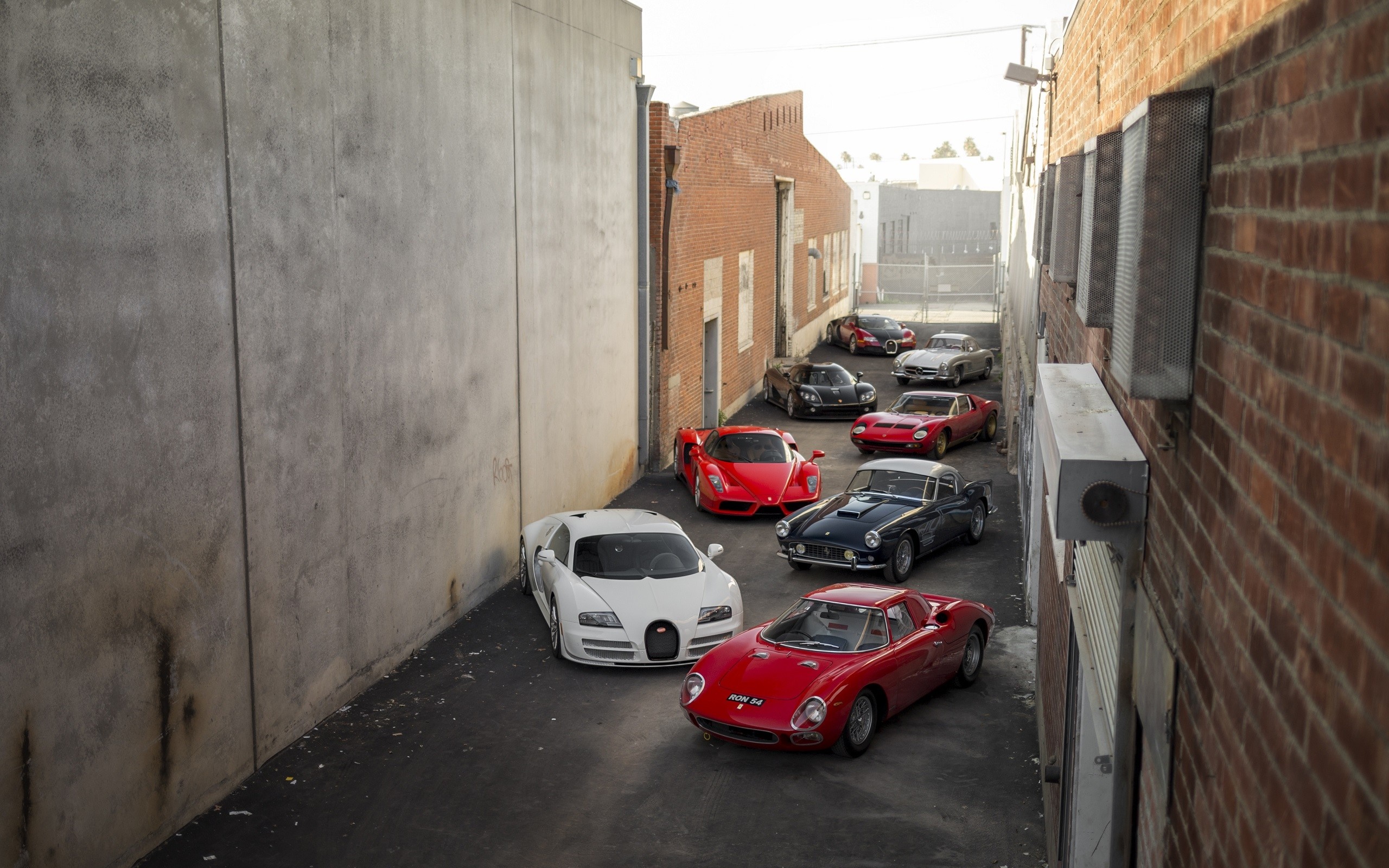 Collection of sports cars including Ferrari, Bugatti, and Mercedes-Benz in an alley HD Wallpaper