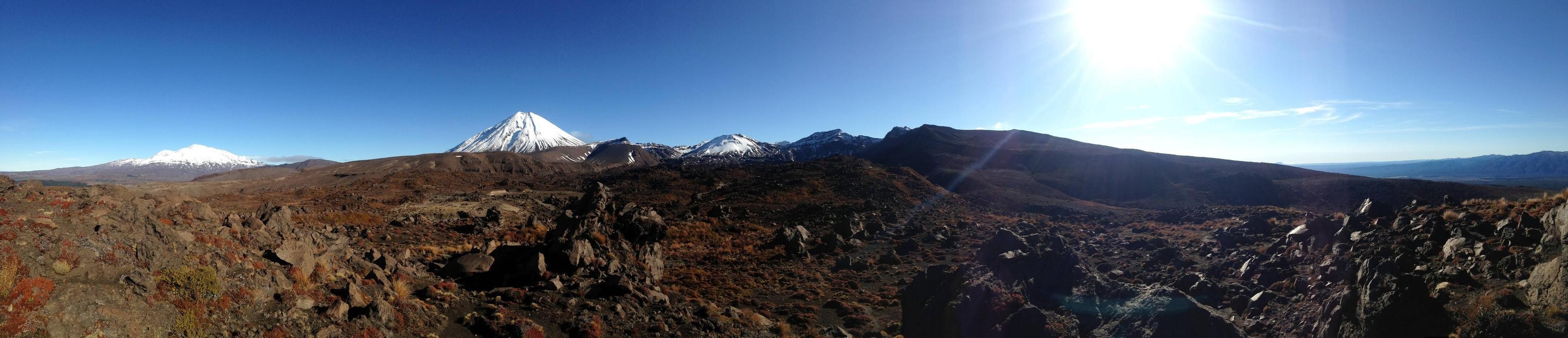 Panoramic view of snow-capped mountains under a clear blue sky HD Wallpaper