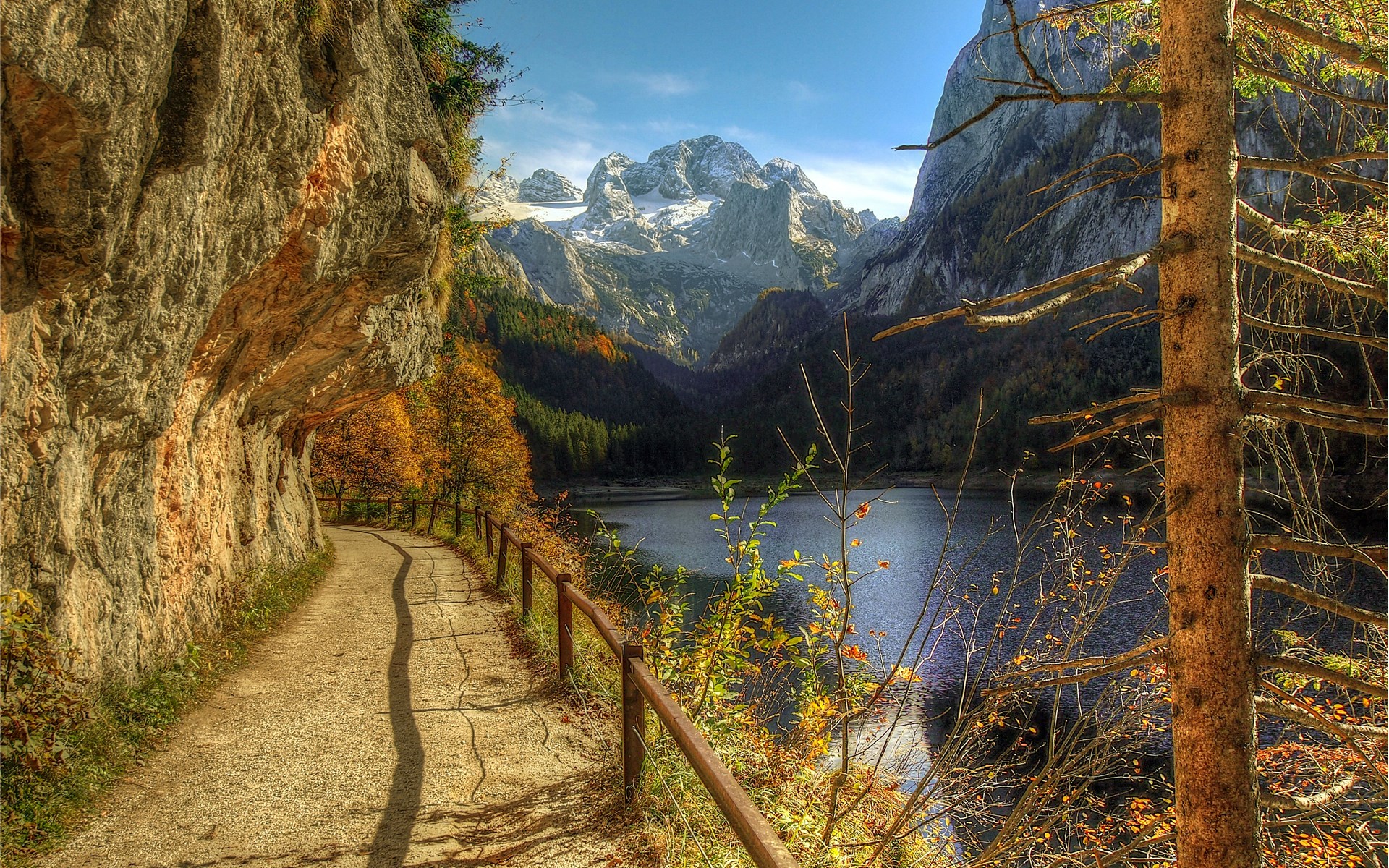 Mountain path beside a lake with snow-capped peaks HD Wallpaper
