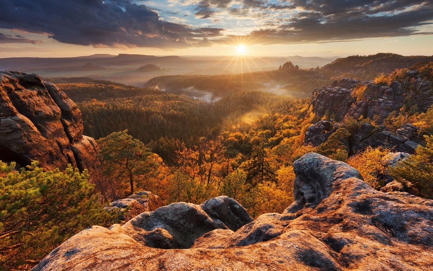 Sunrise over a misty autumn forest valley with rocky outcrops HD Wallpaper