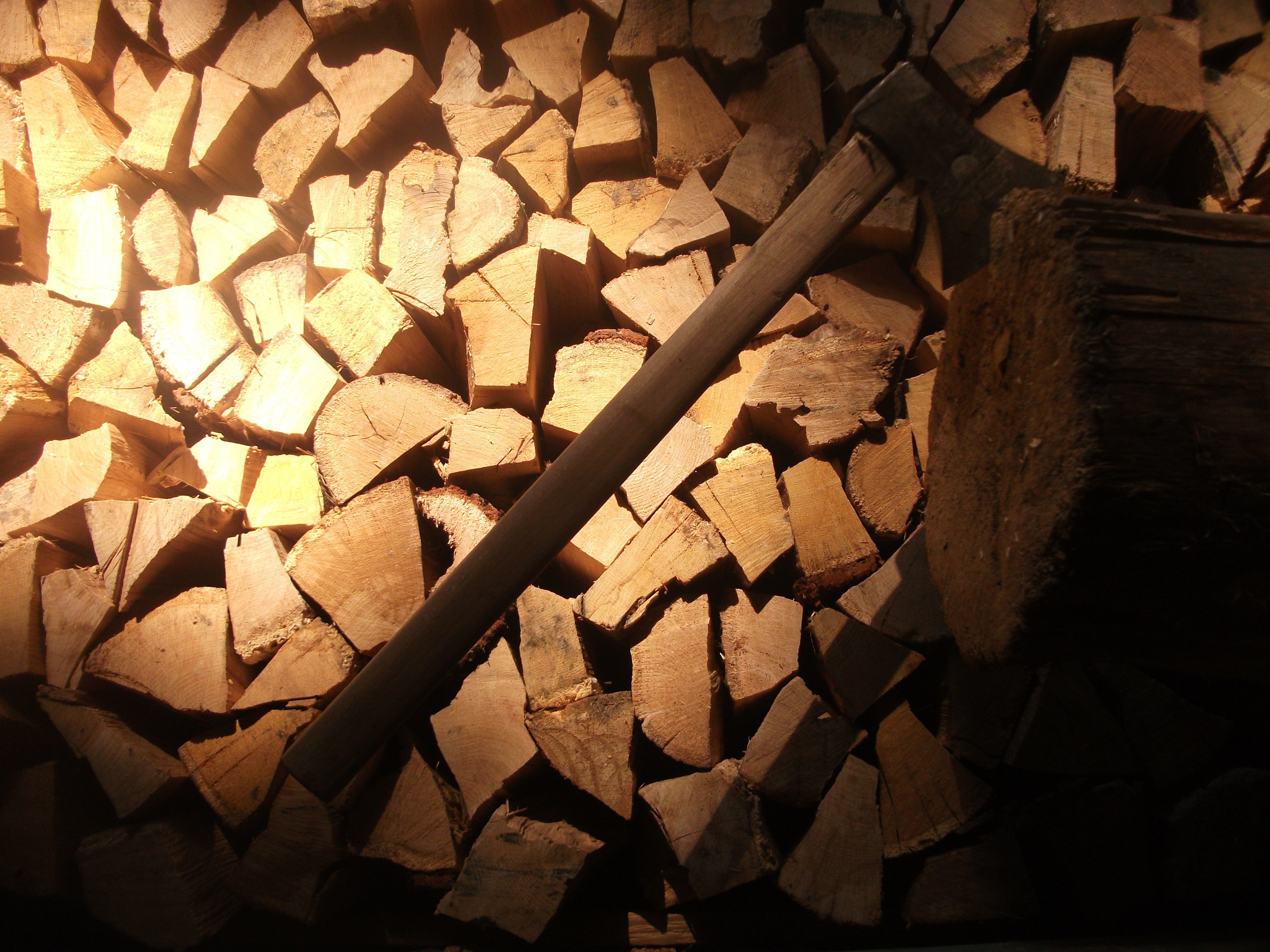 Pile of chopped firewood with an axe HD Wallpaper