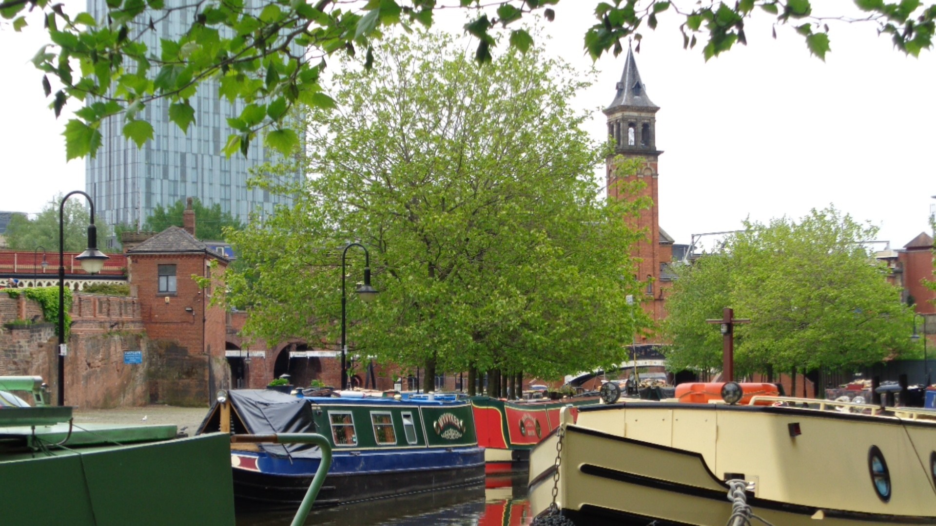 Boats on a canal with a modern building and clock tower HD Wallpaper