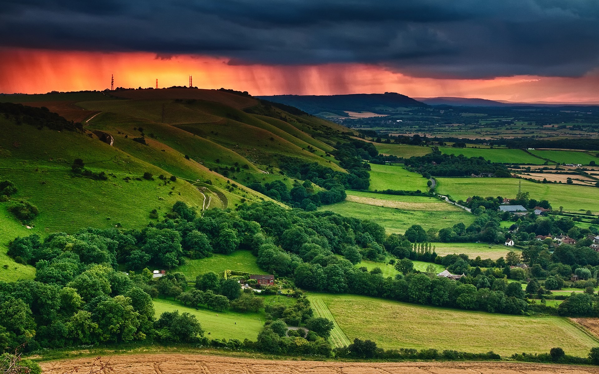 Rolling green hills under a stormy sunset sky HD Wallpaper