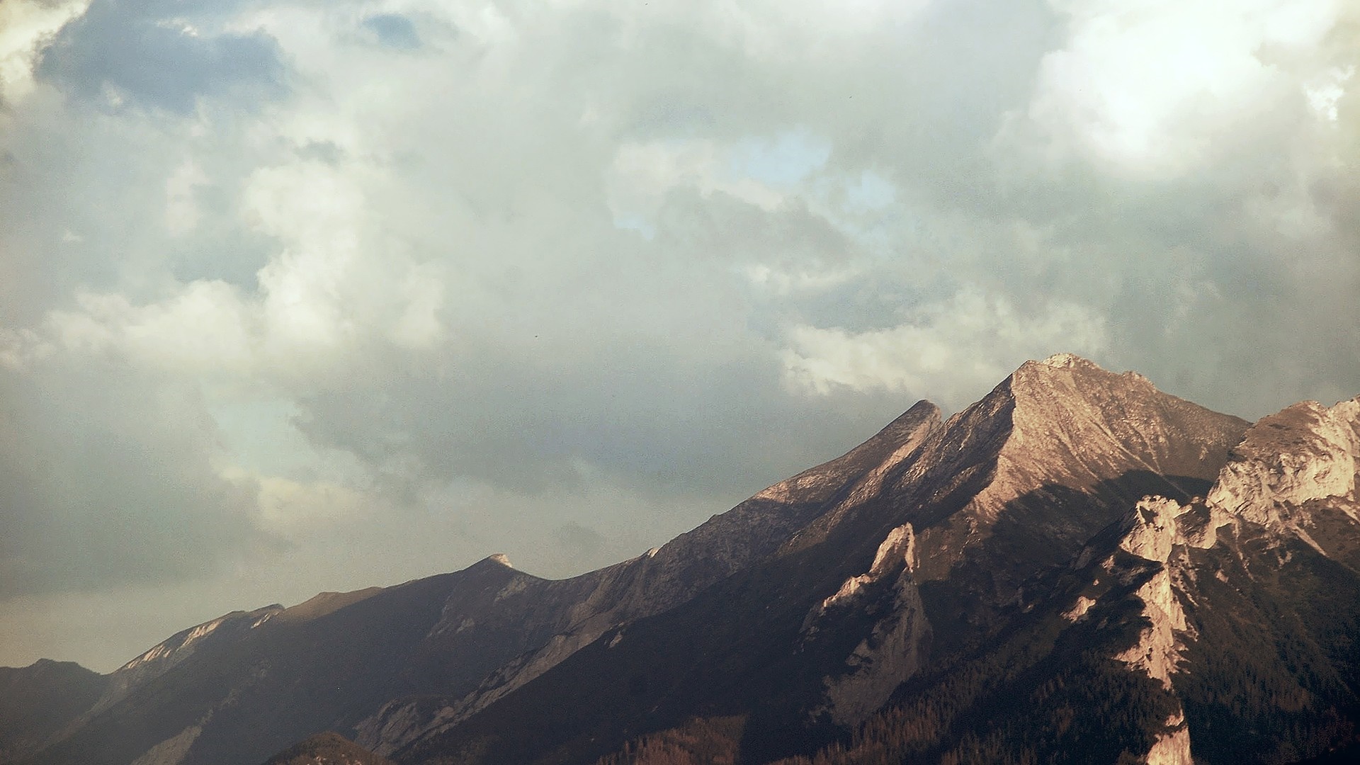 Sunlight on mountain peaks under cloudy sky HD Wallpaper