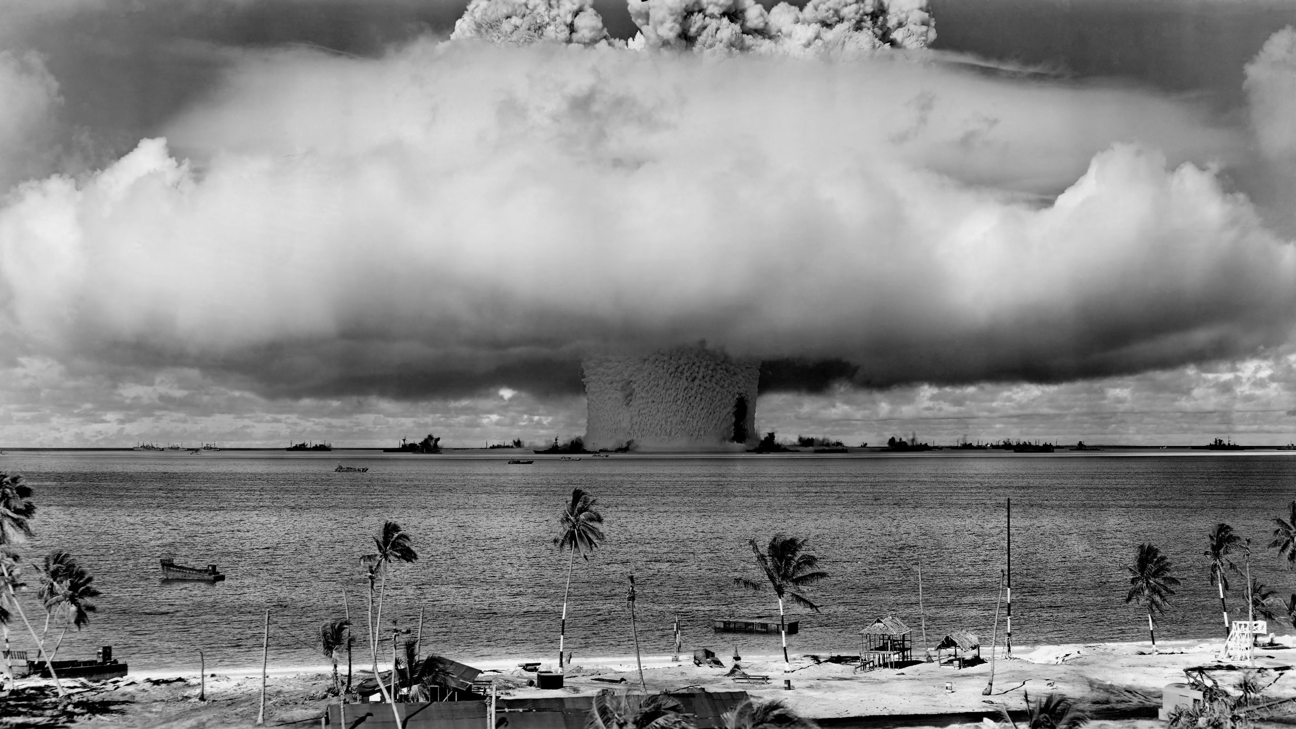 Nuclear explosion over the ocean with ships and palm trees HD Wallpaper