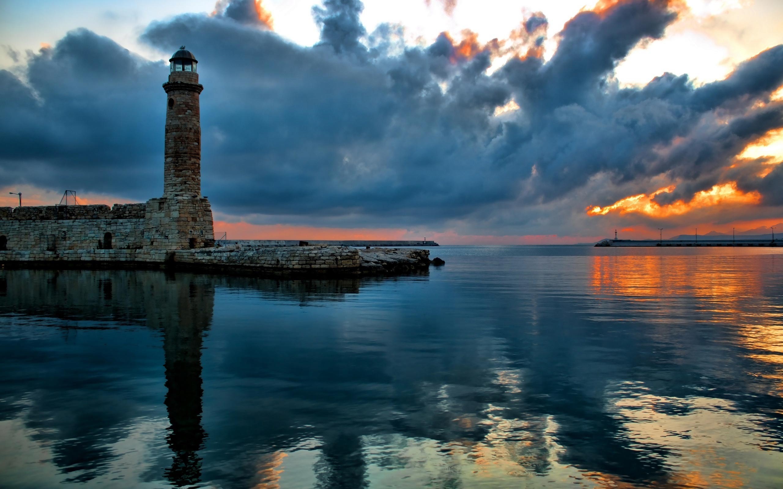 Lighthouse at dusk with dramatic clouds over the sea HD Wallpaper