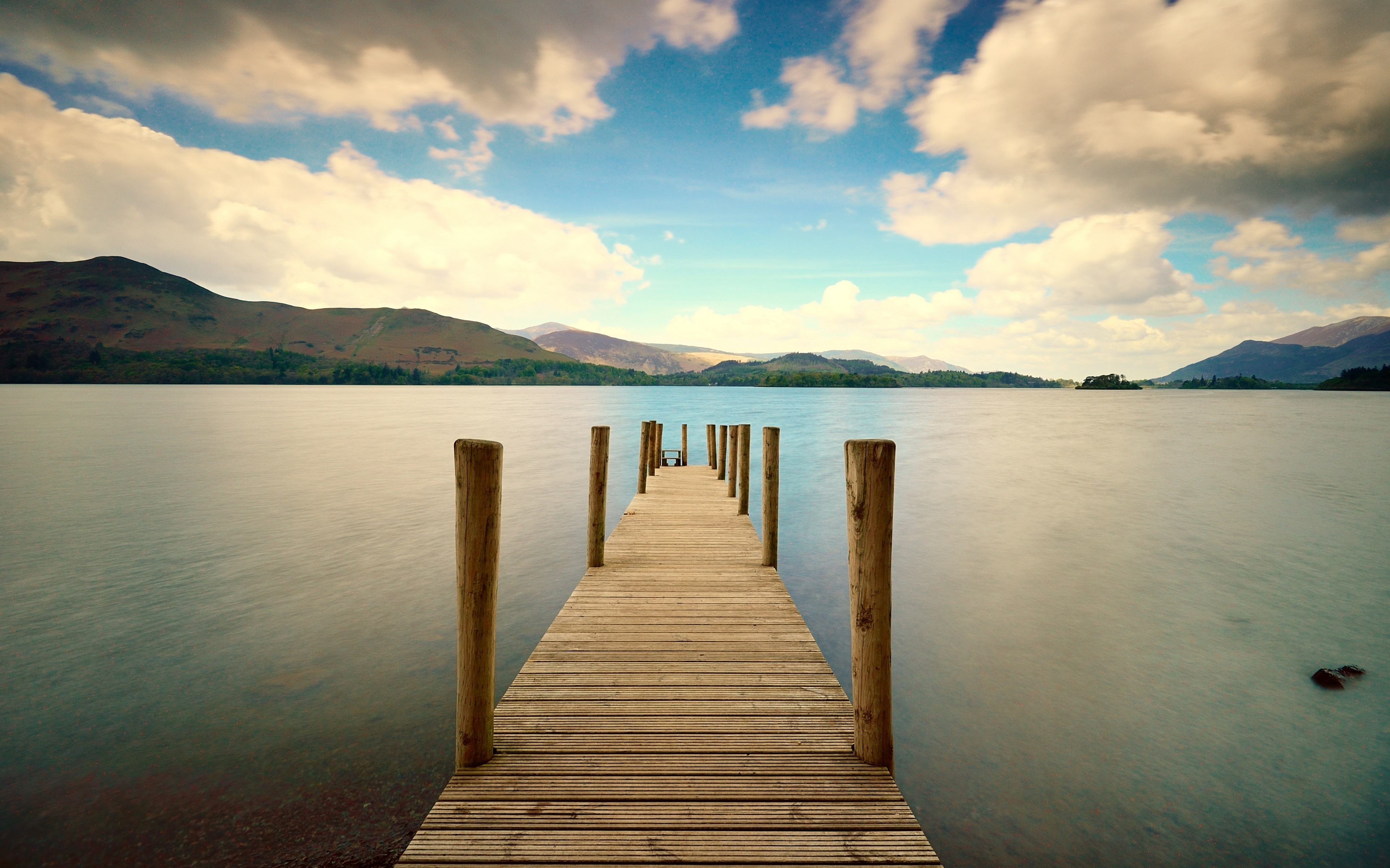 Wooden pier on a calm lake with mountains in the background HD Wallpaper