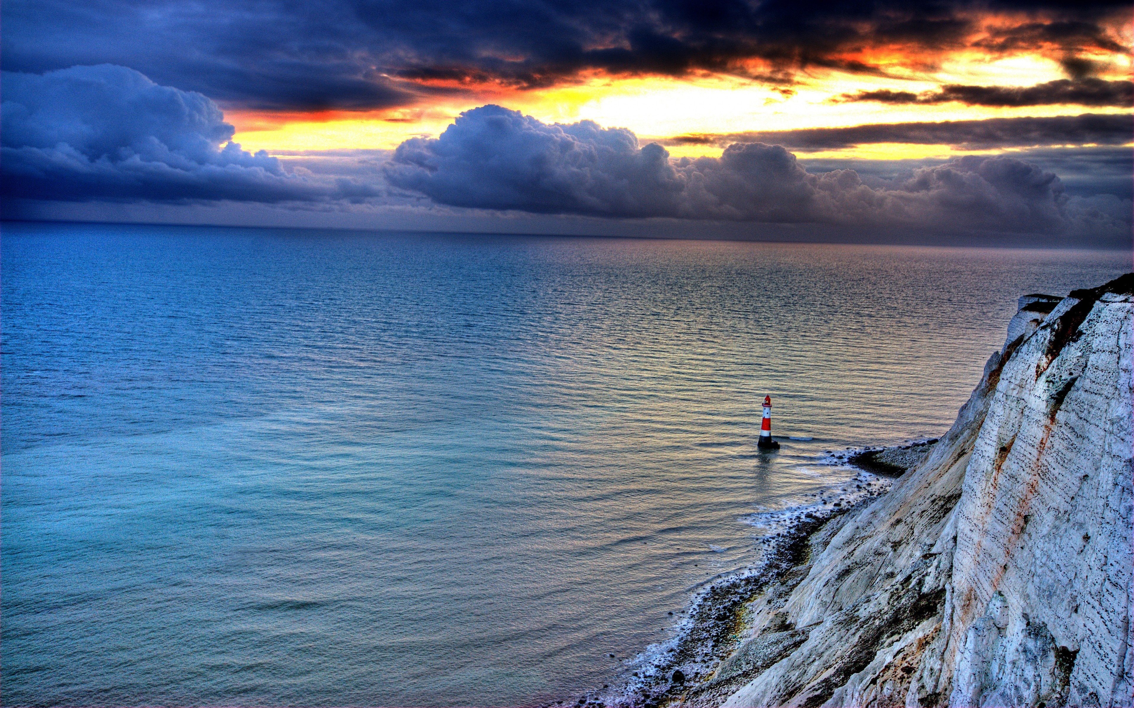 Sunset over the sea with a lighthouse and cliff HD Wallpaper