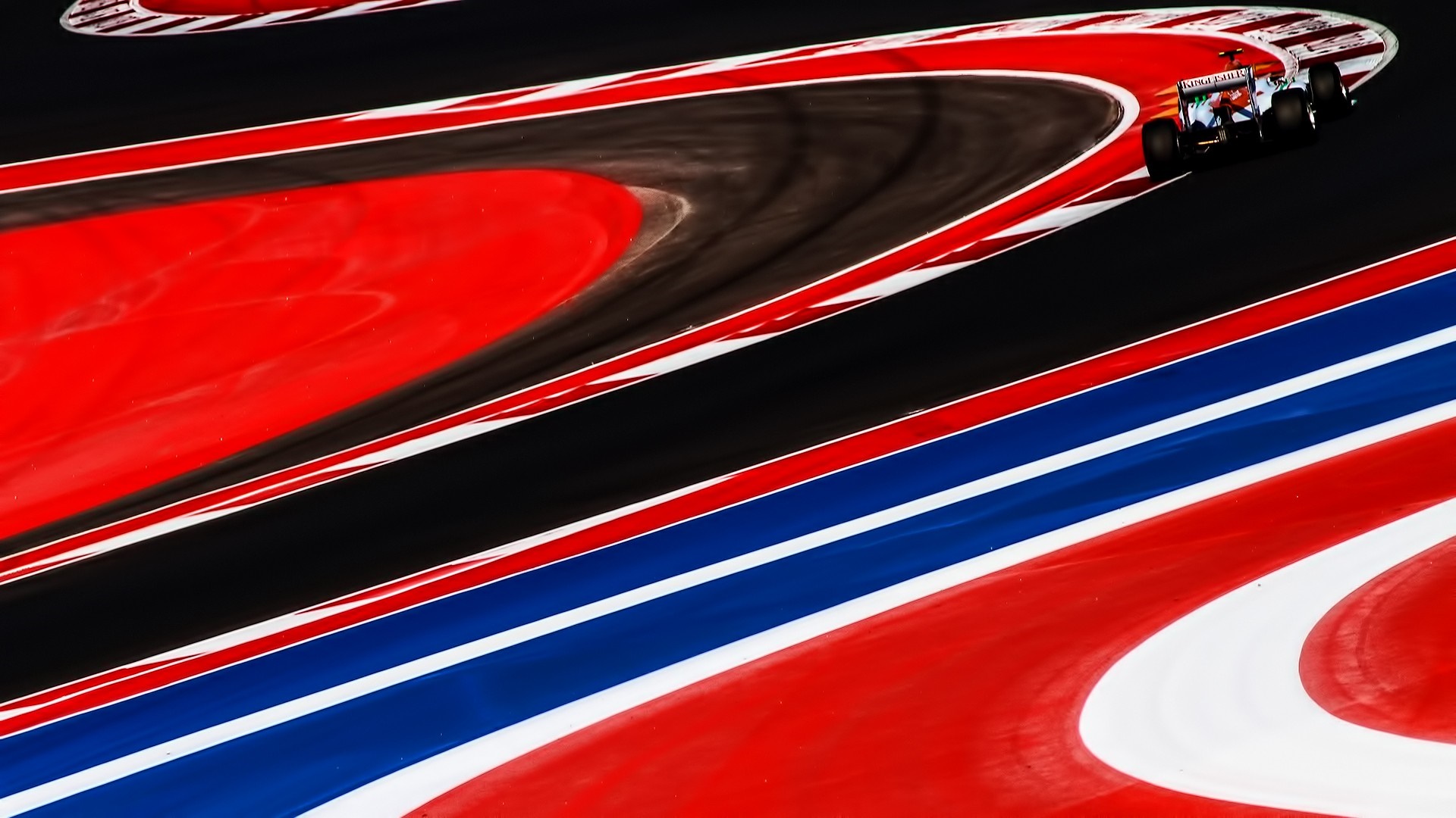 Formula 1 car on a red and black race track HD Wallpaper