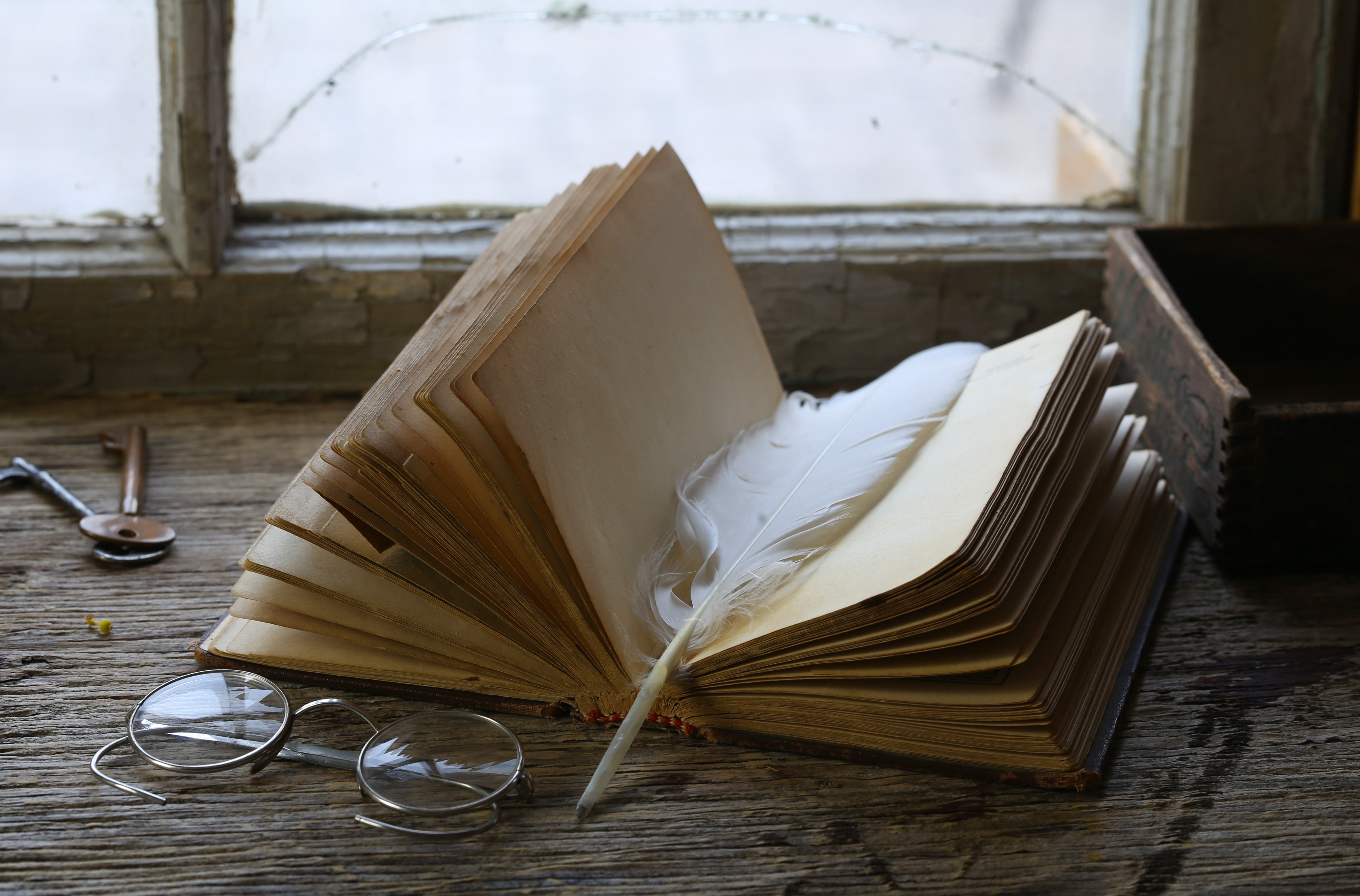 Vintage book with feather, glasses, and keys by window HD Wallpaper