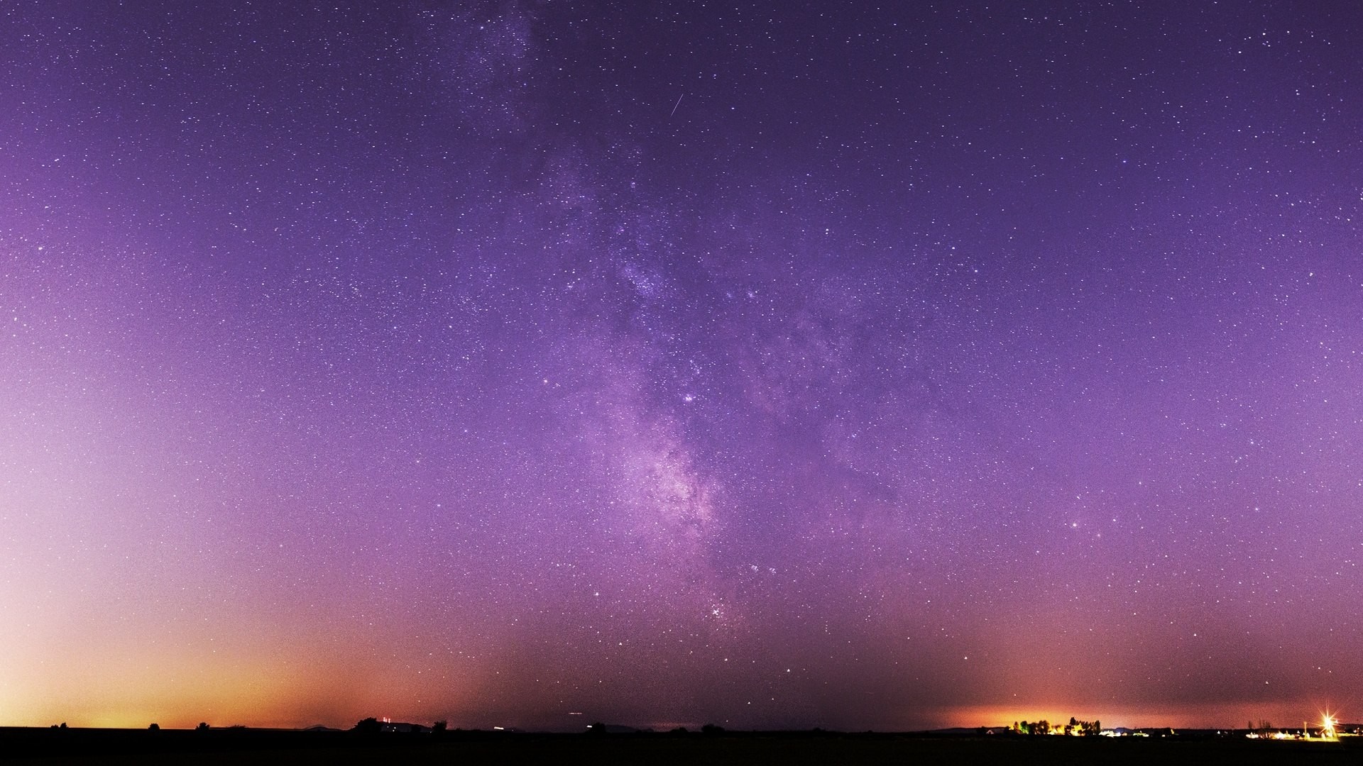 Milky Way galaxy over a dark landscape with city lights HD Wallpaper