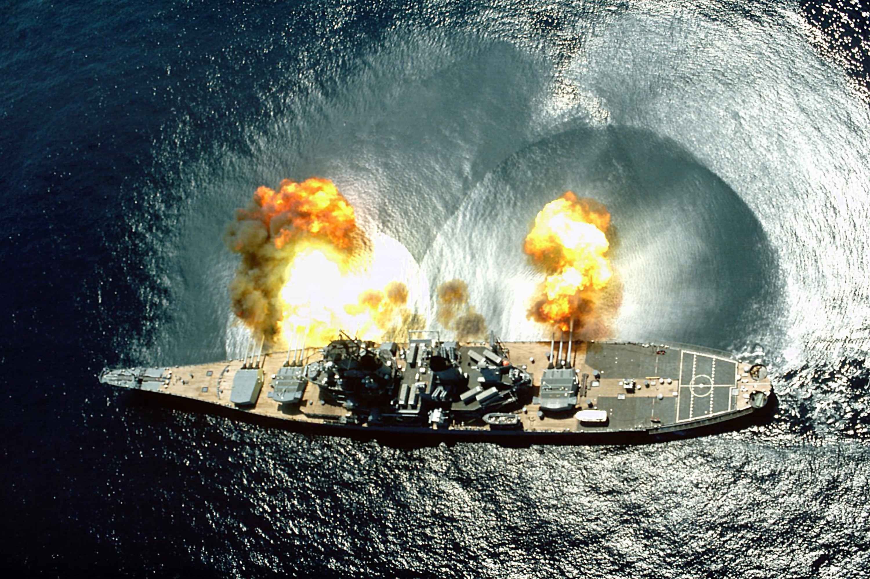 Battleship firing its guns into the ocean HD Wallpaper