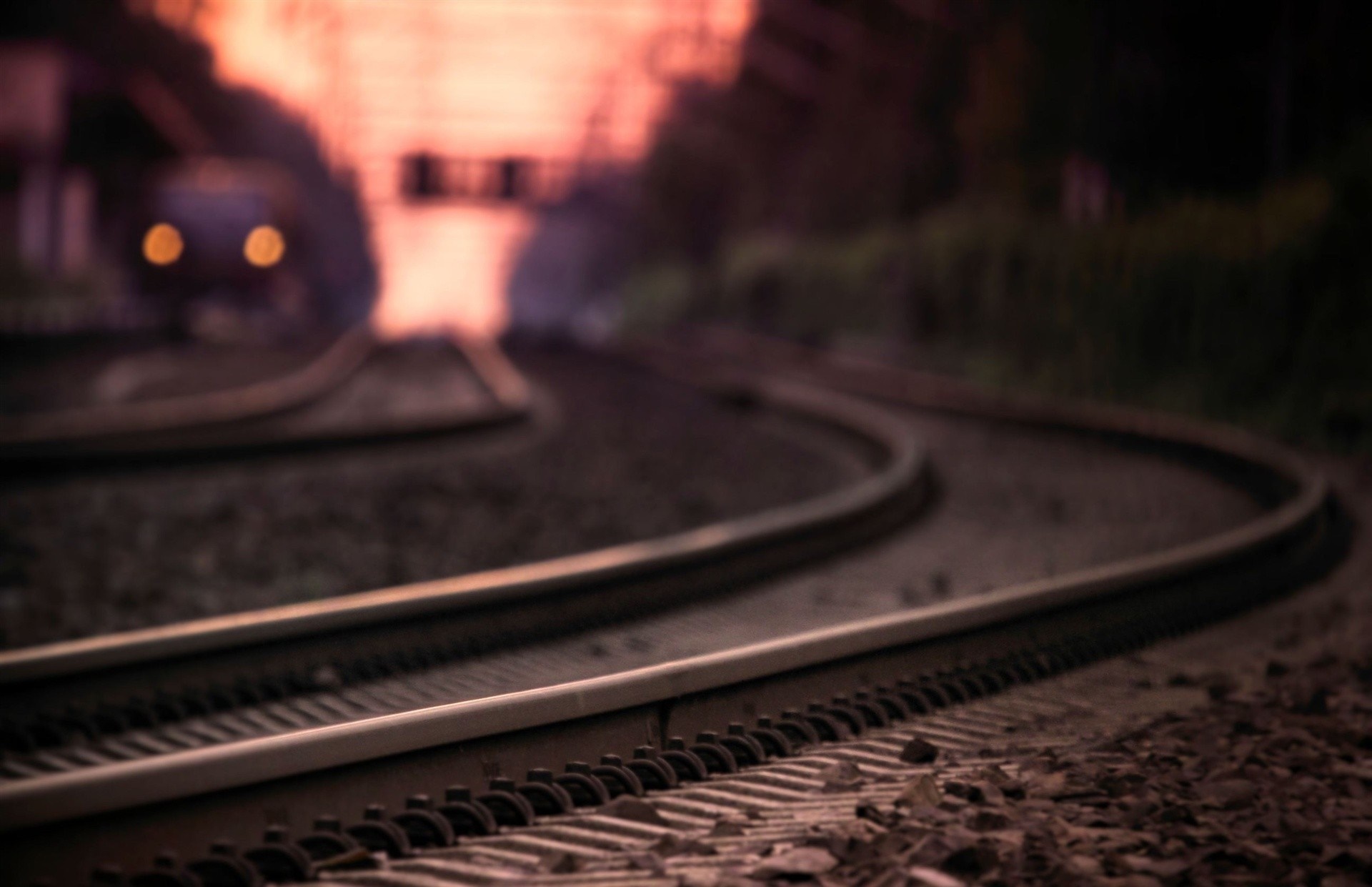 Train tracks curving at sunset with a train in the distance HD Wallpaper