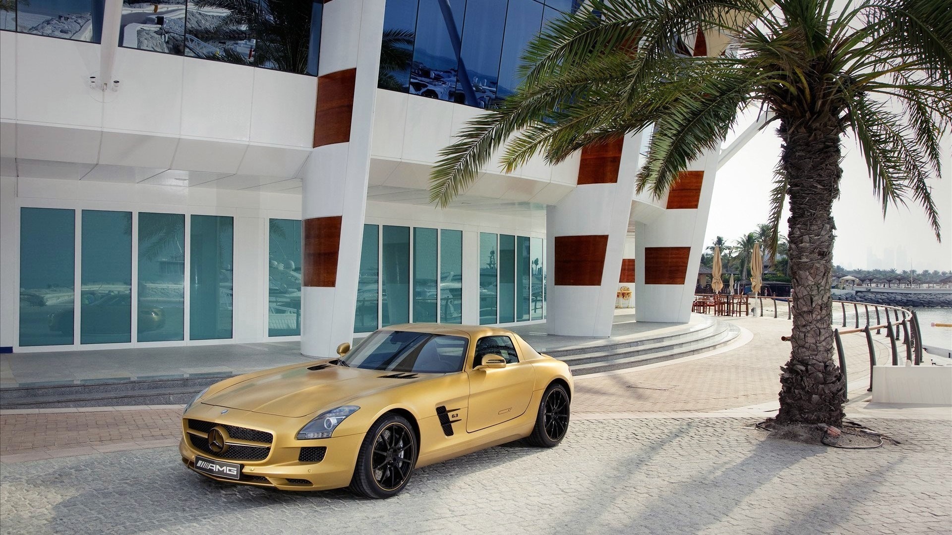 Gold Mercedes-Benz SLS AMG parked outside modern building HD Wallpaper