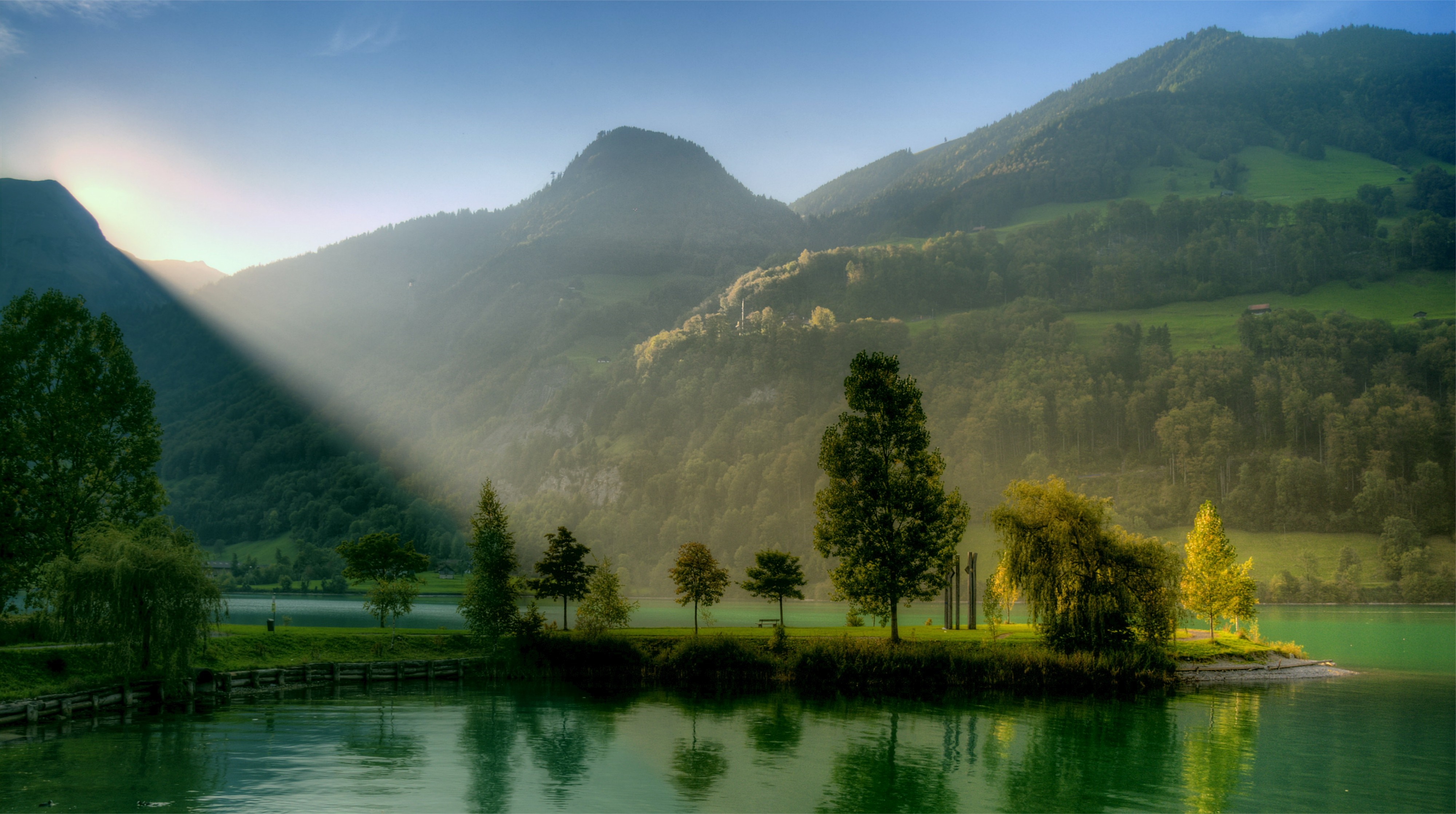 Sunlight beams over a misty mountain lake landscape HD Wallpaper