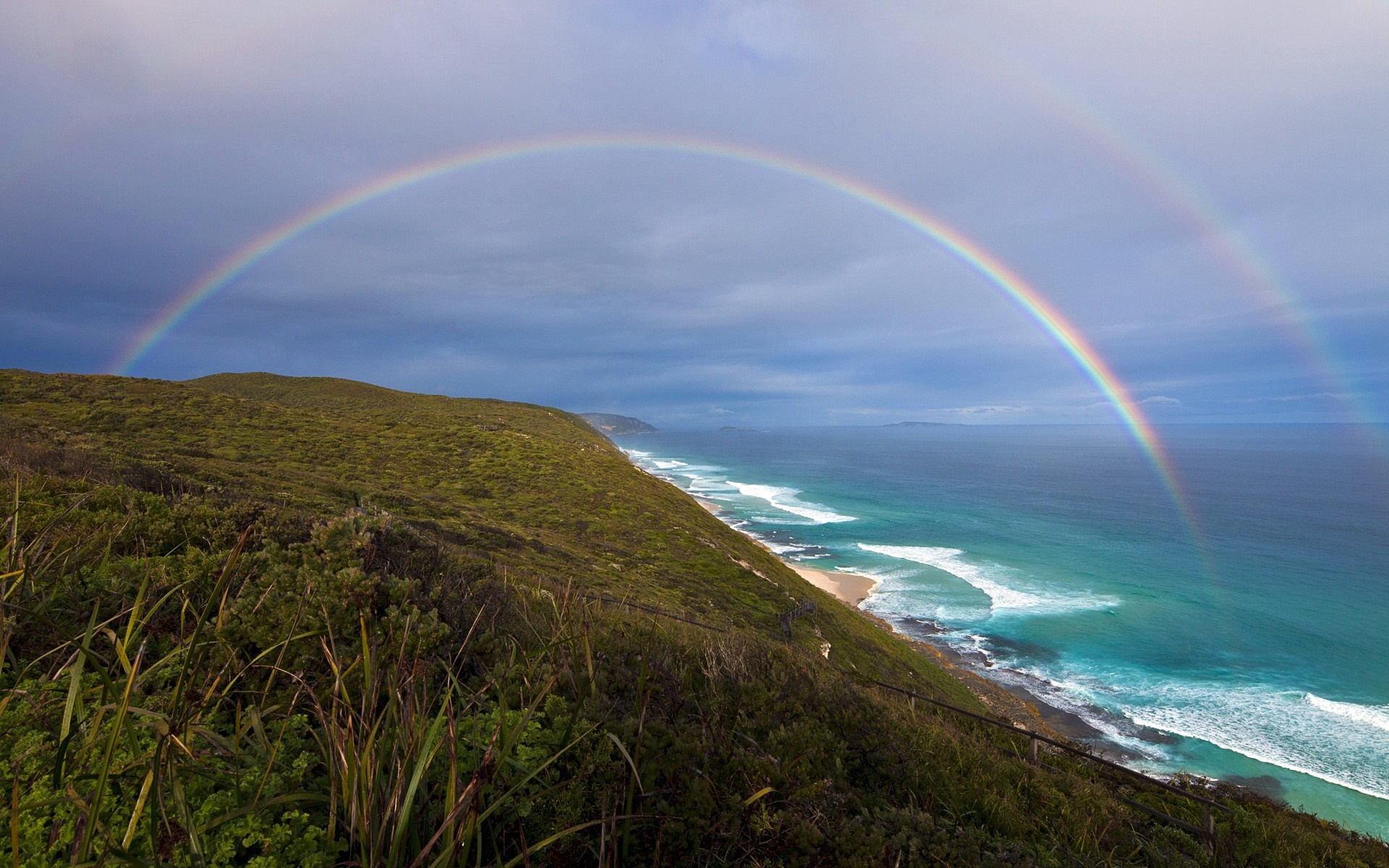 Double rainbow over a green coastal hill and ocean HD Wallpaper