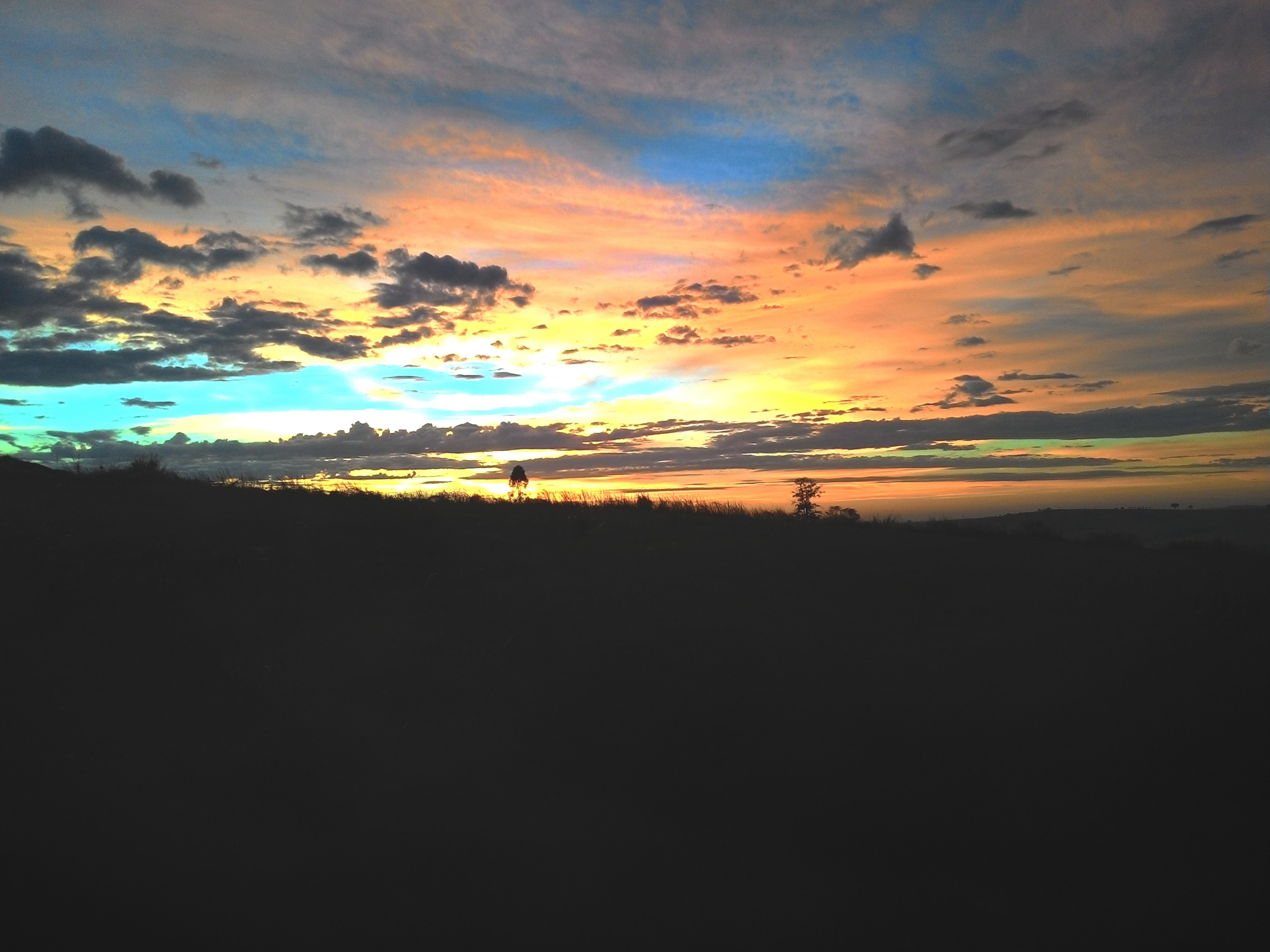 Sunset over a silhouetted landscape with colorful clouds HD Wallpaper