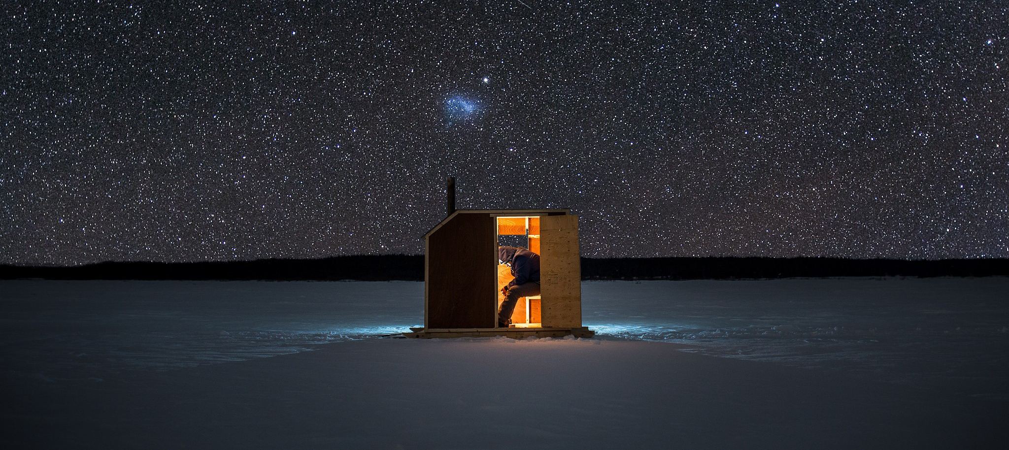 Person in illuminated hut under starry night sky HD Wallpaper