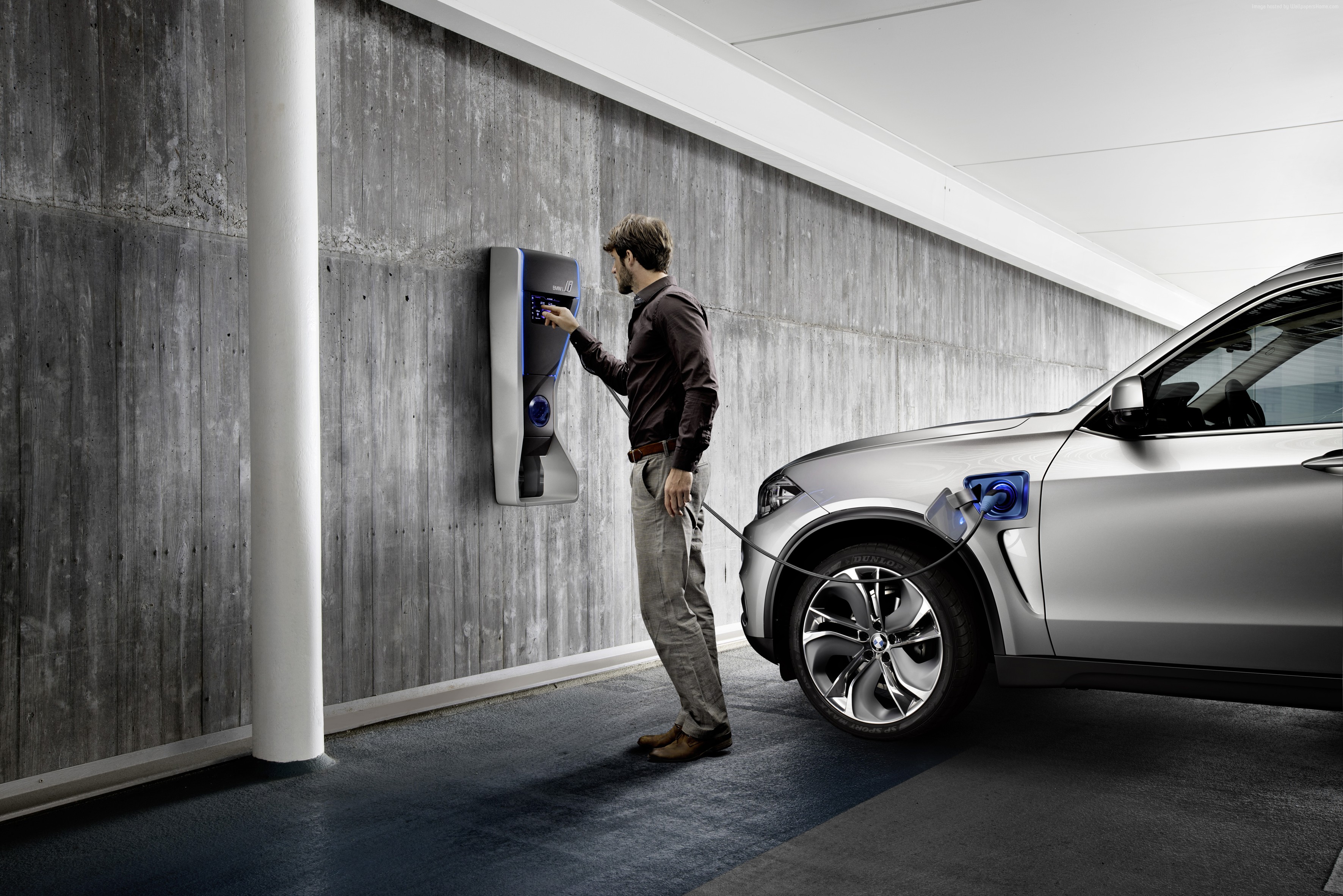 Man charging BMW X5 xDrive40e hybrid SUV HD Wallpaper