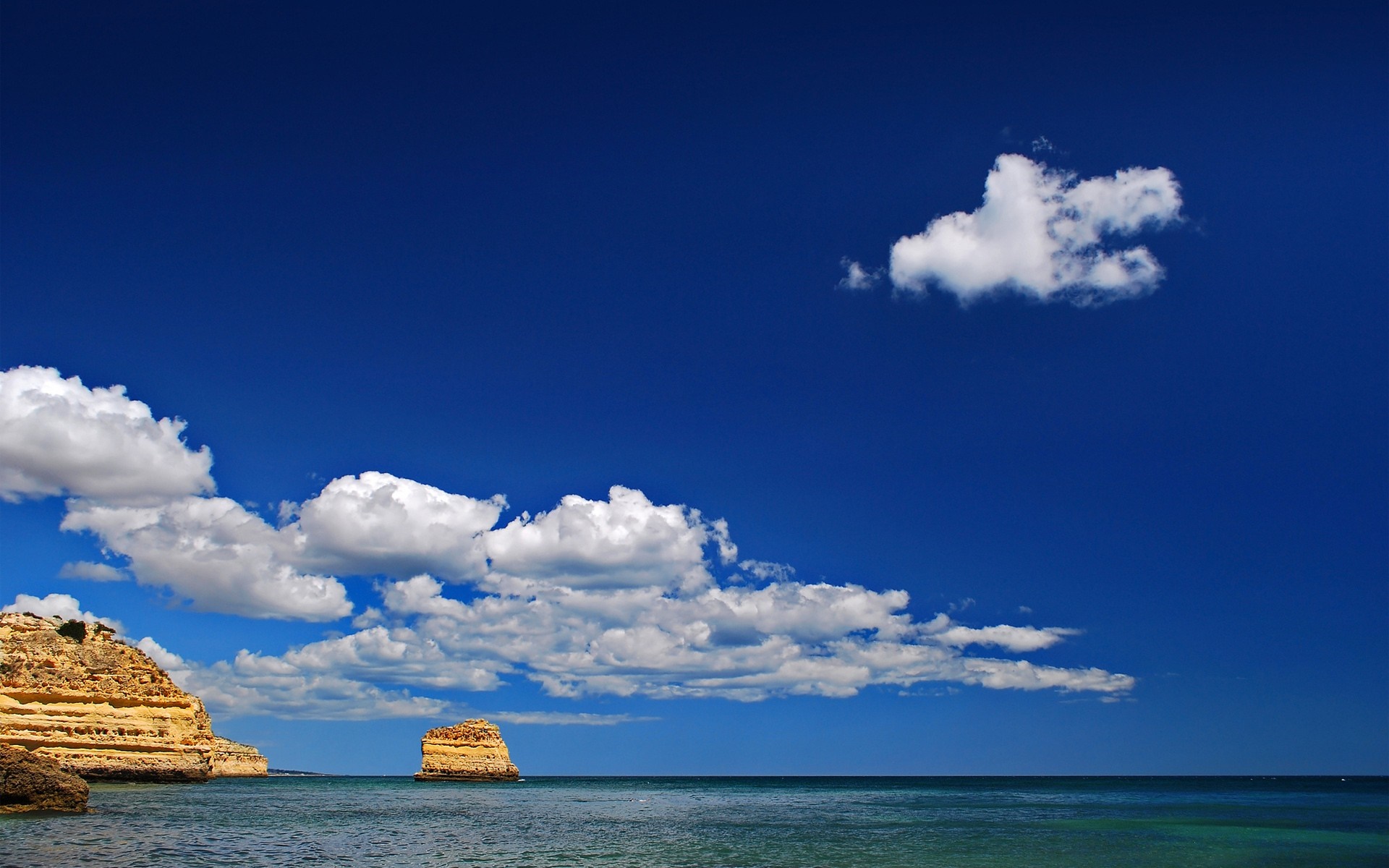 Rocky coast and sea under a blue sky with clouds HD Wallpaper
