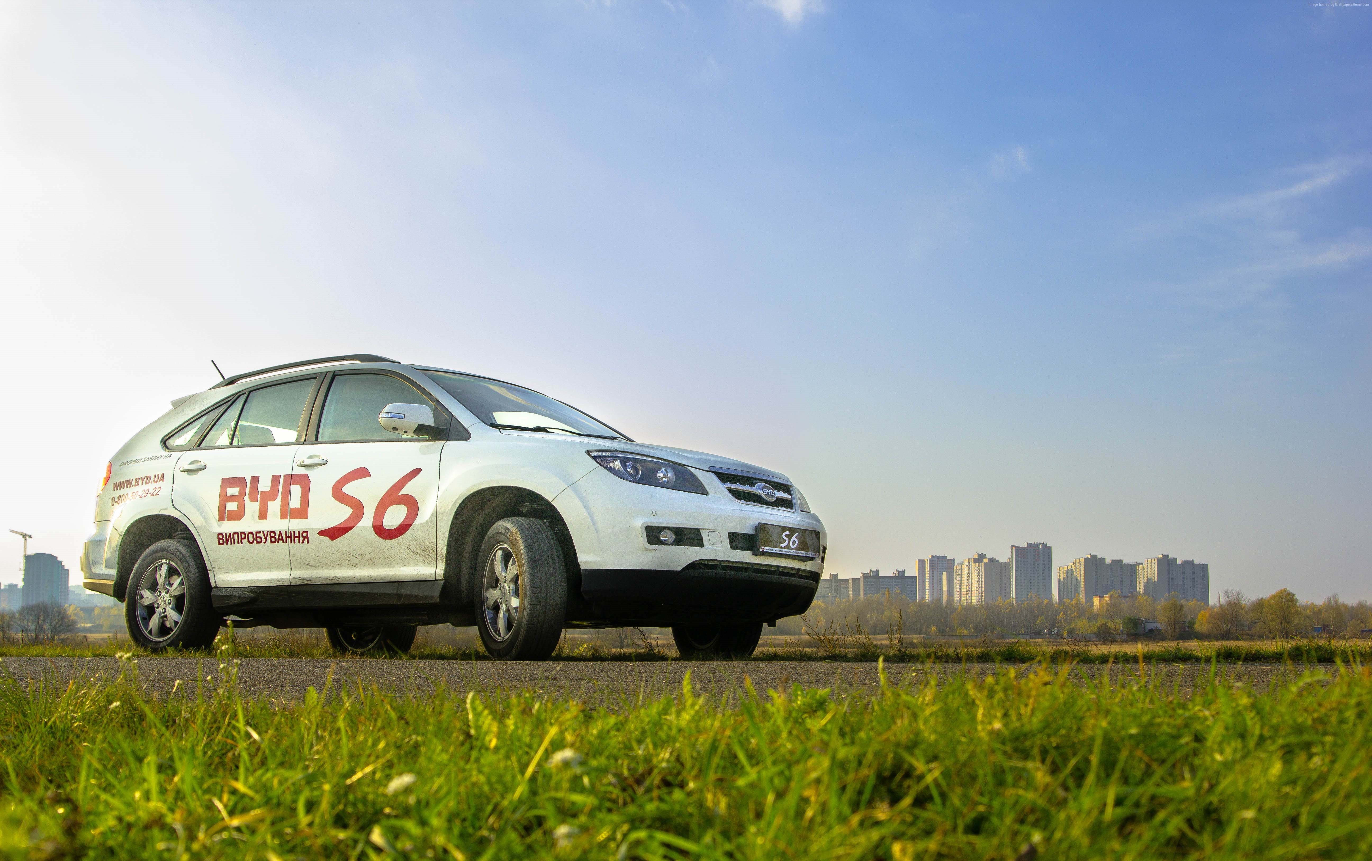 White BYD S6 hybrid car on road with city skyline HD Wallpaper