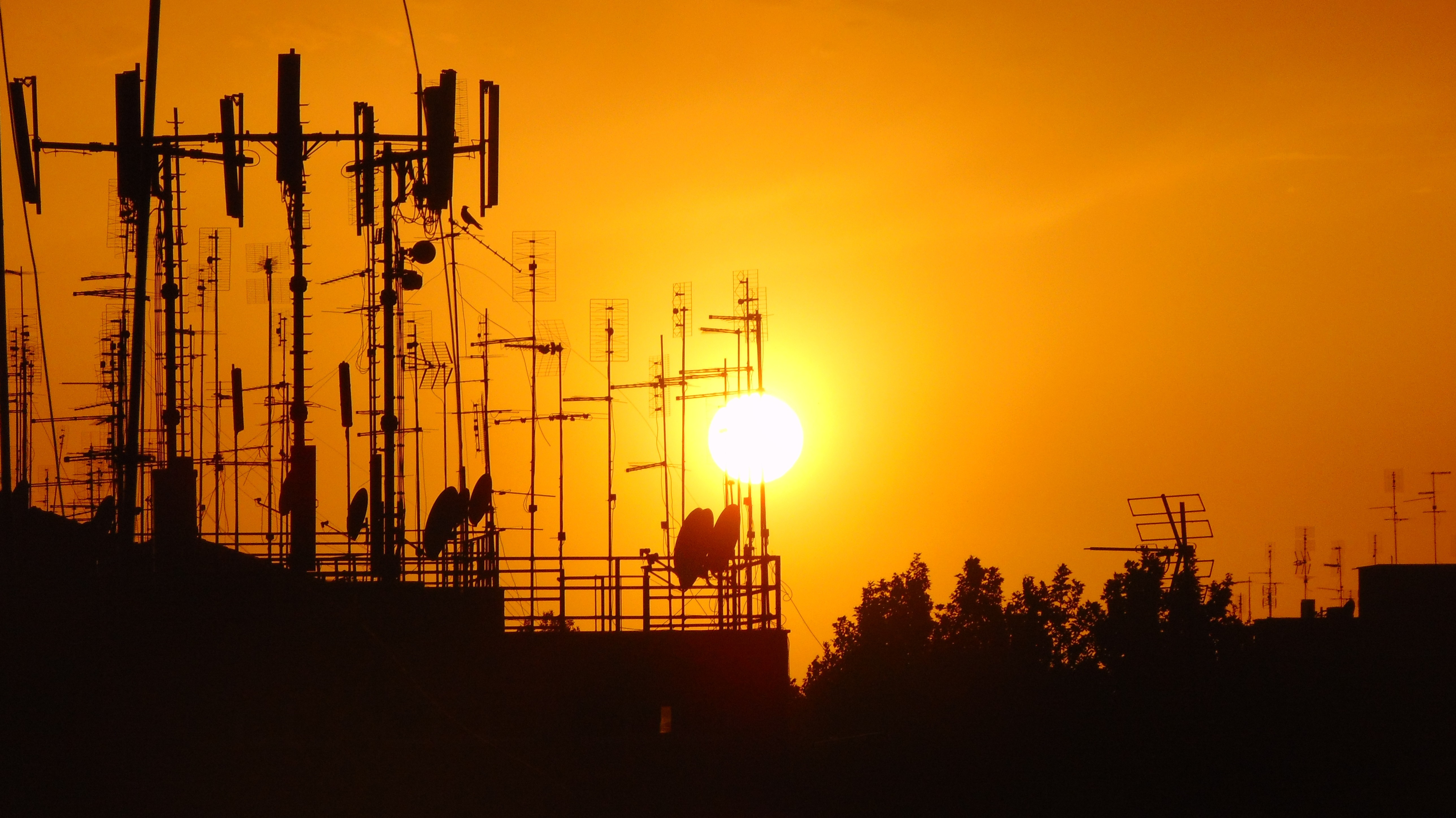 Cell towers and antennas silhouetted against a sunset HD Wallpaper