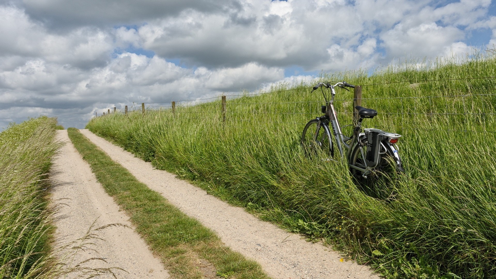 Dirt path through grassy hill with a bicycle HD Wallpaper