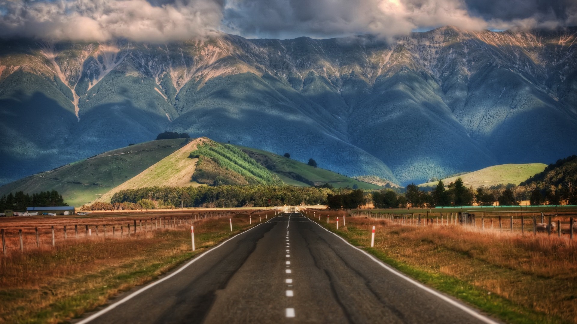 Road leading to mountains under cloudy sky HD Wallpaper
