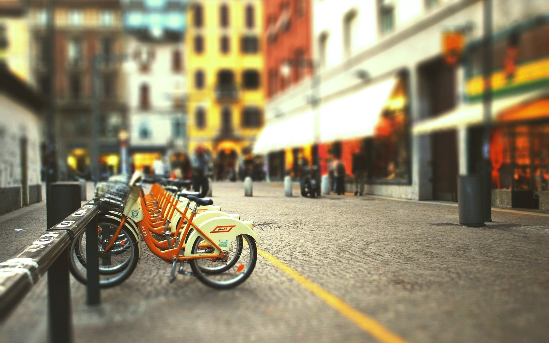 Row of rental bicycles parked on a cobblestone street in a city HD Wallpaper