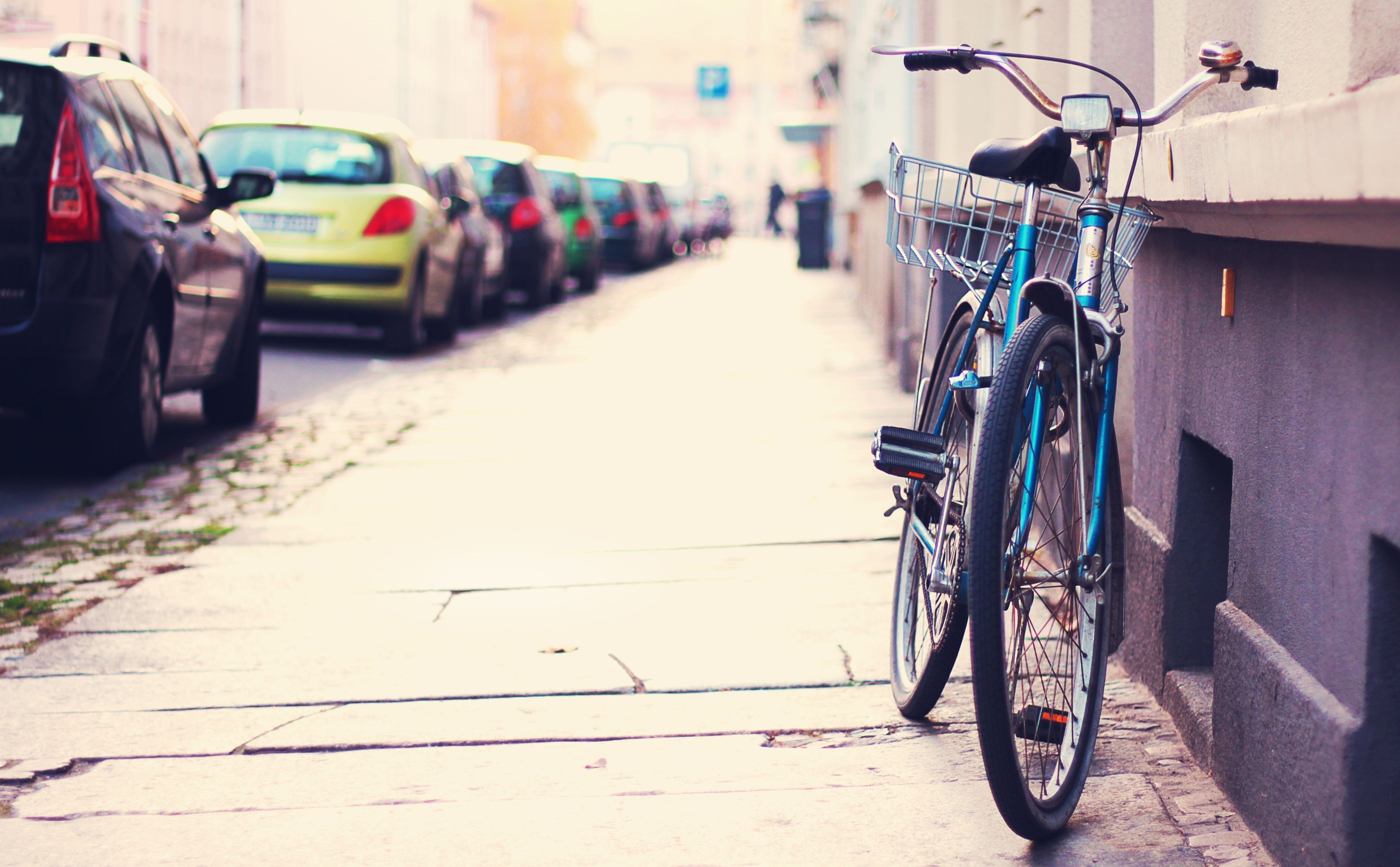 Blue bicycle parked on a city street next to parked cars HD Wallpaper