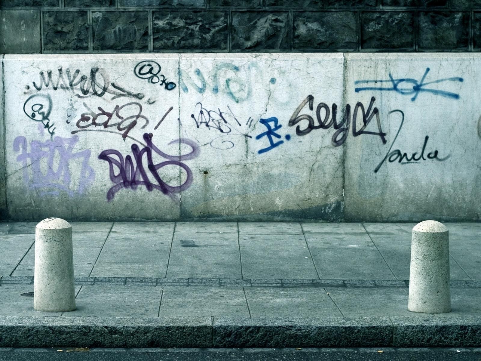 Graffiti on a concrete wall with bollards HD Wallpaper