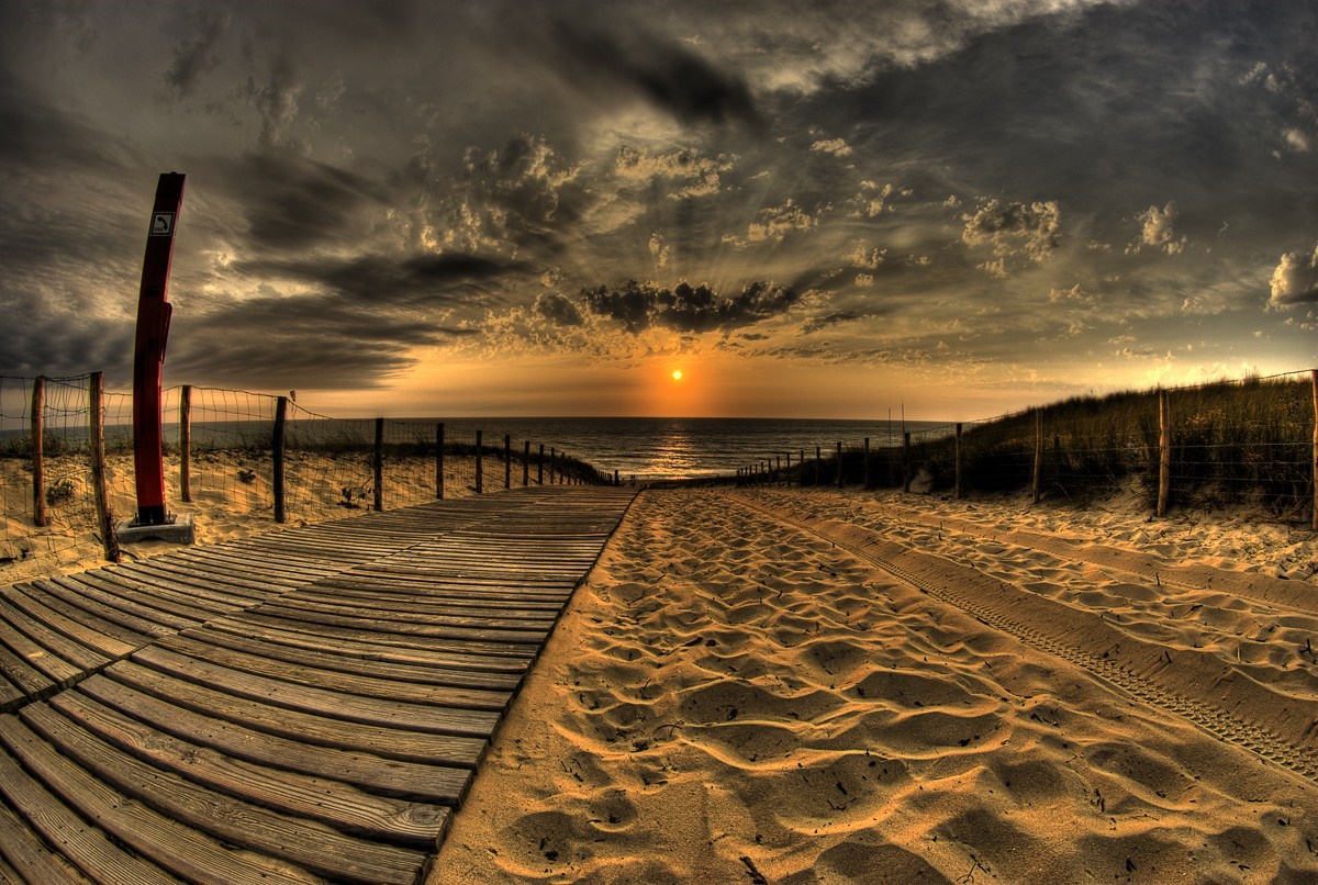Wooden boardwalk and sandy path leading to the ocean at sunset HD Wallpaper