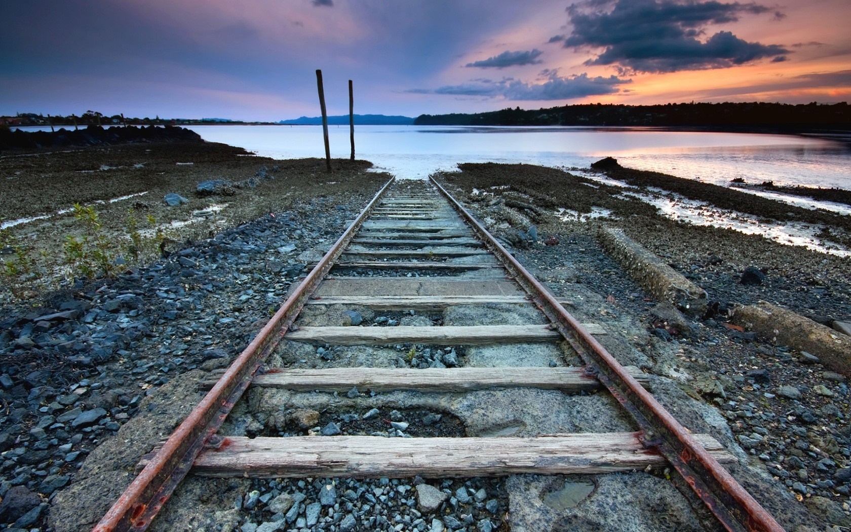 Abandoned railway tracks leading to the sea at sunset HD Wallpaper